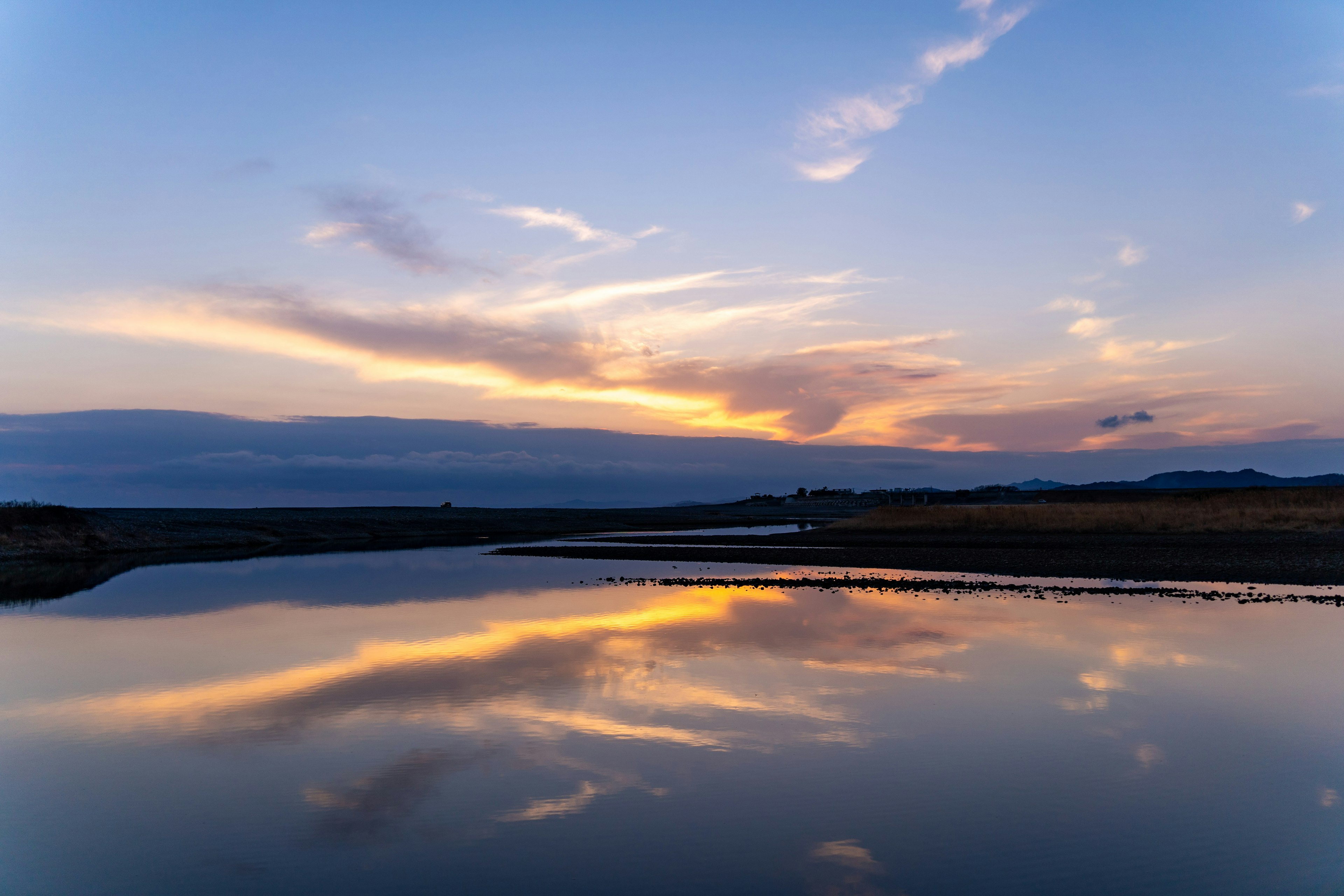 夕焼けの空と静かな川の反射が美しい風景