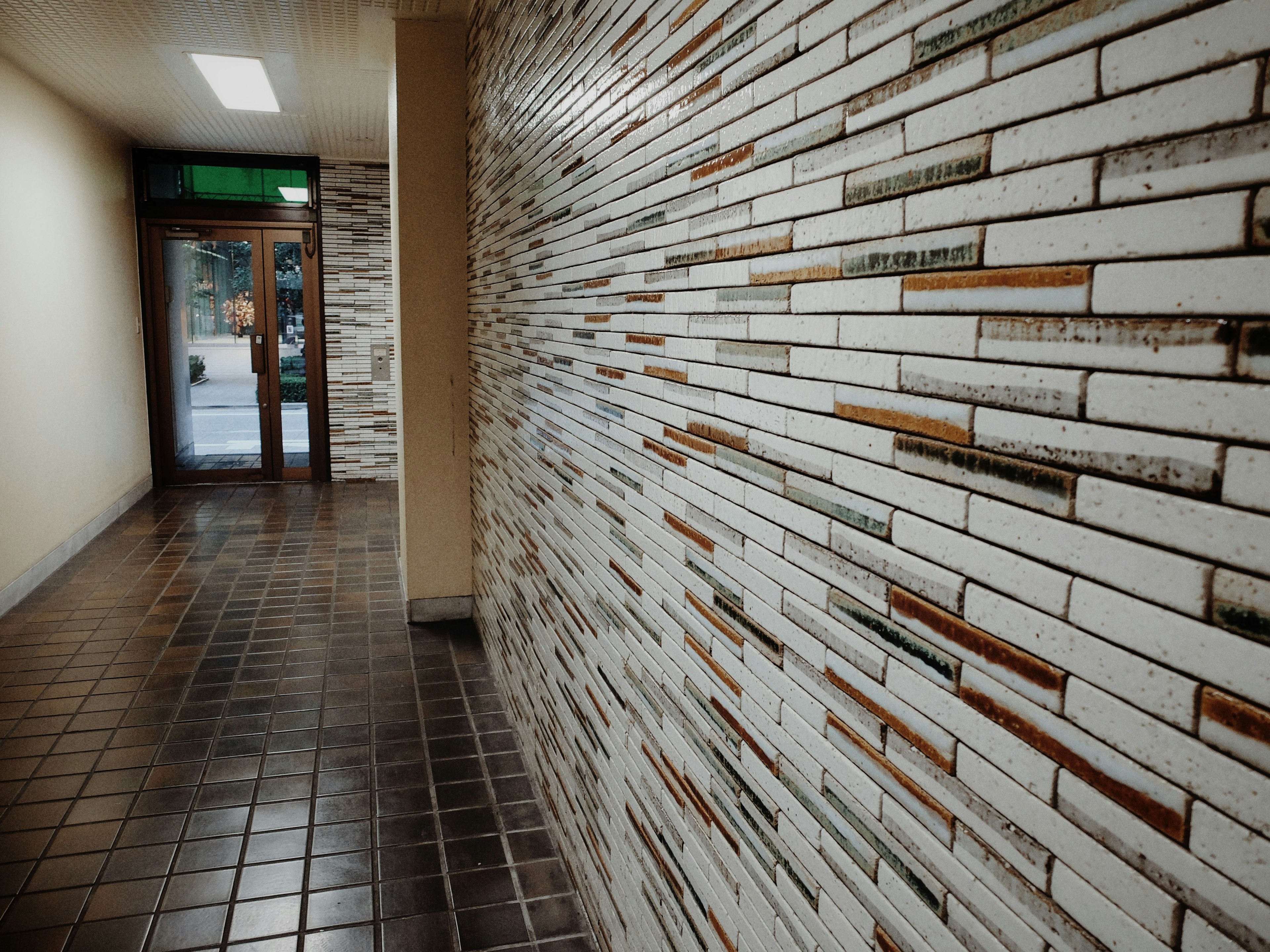 Foto de un pasillo con una pared de azulejos blancos y un suelo de azulejos negros