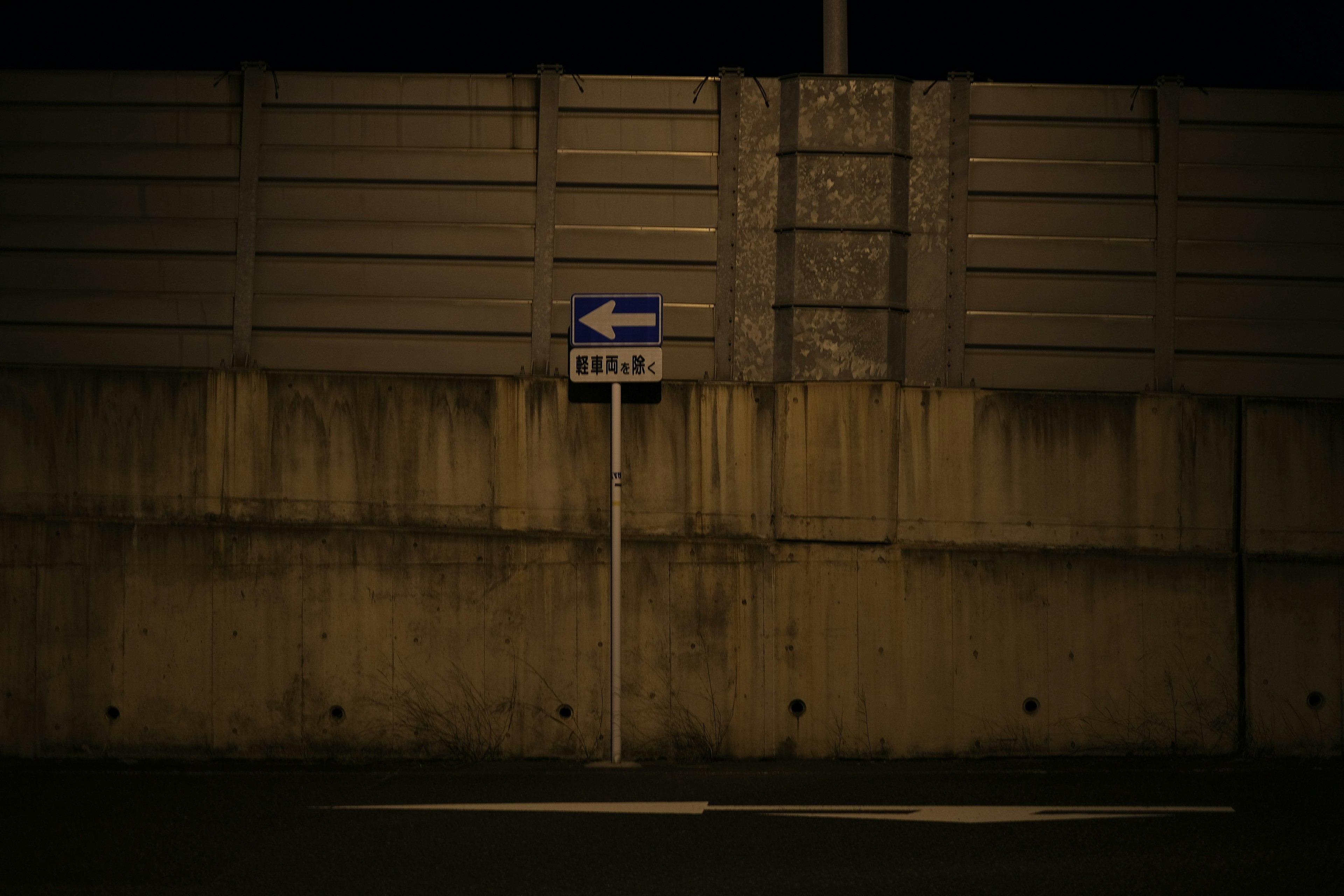 Panneau de signalisation pour tourner à gauche à côté d'un mur en béton dans un cadre sombre