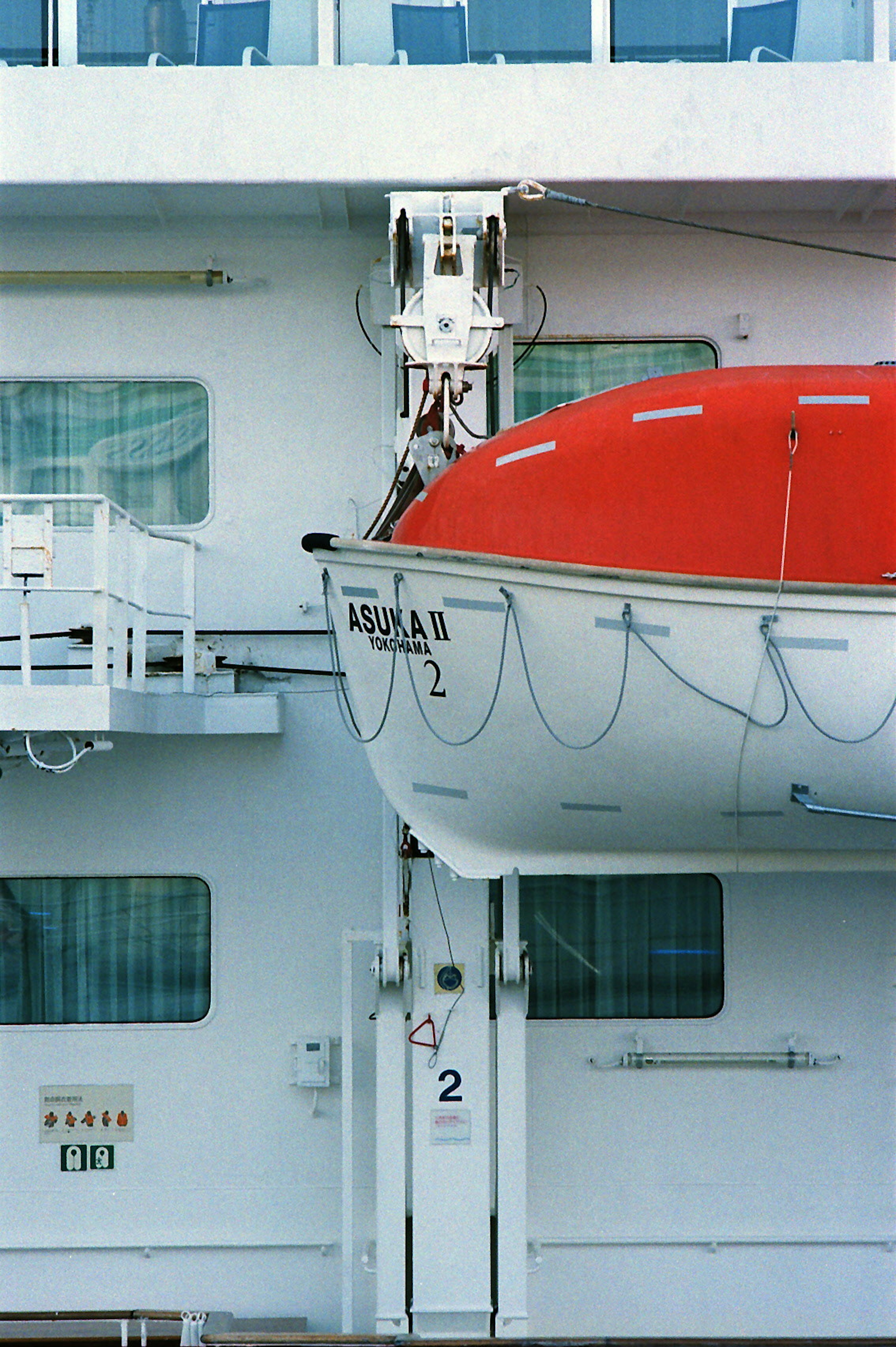 A red lifeboat suspended from the side of a ship