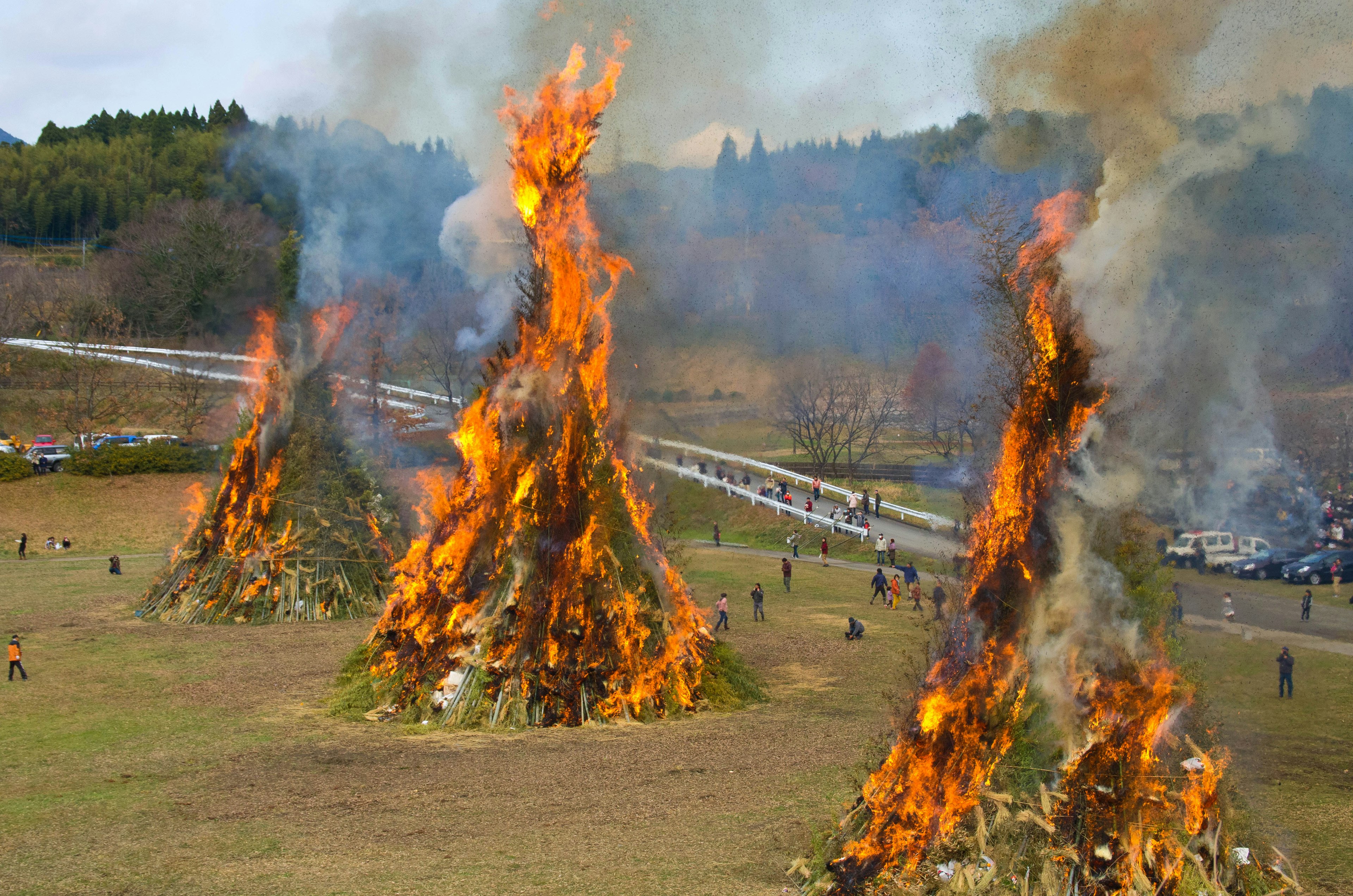 Large bonfires burning with smoke rising in a grassy field