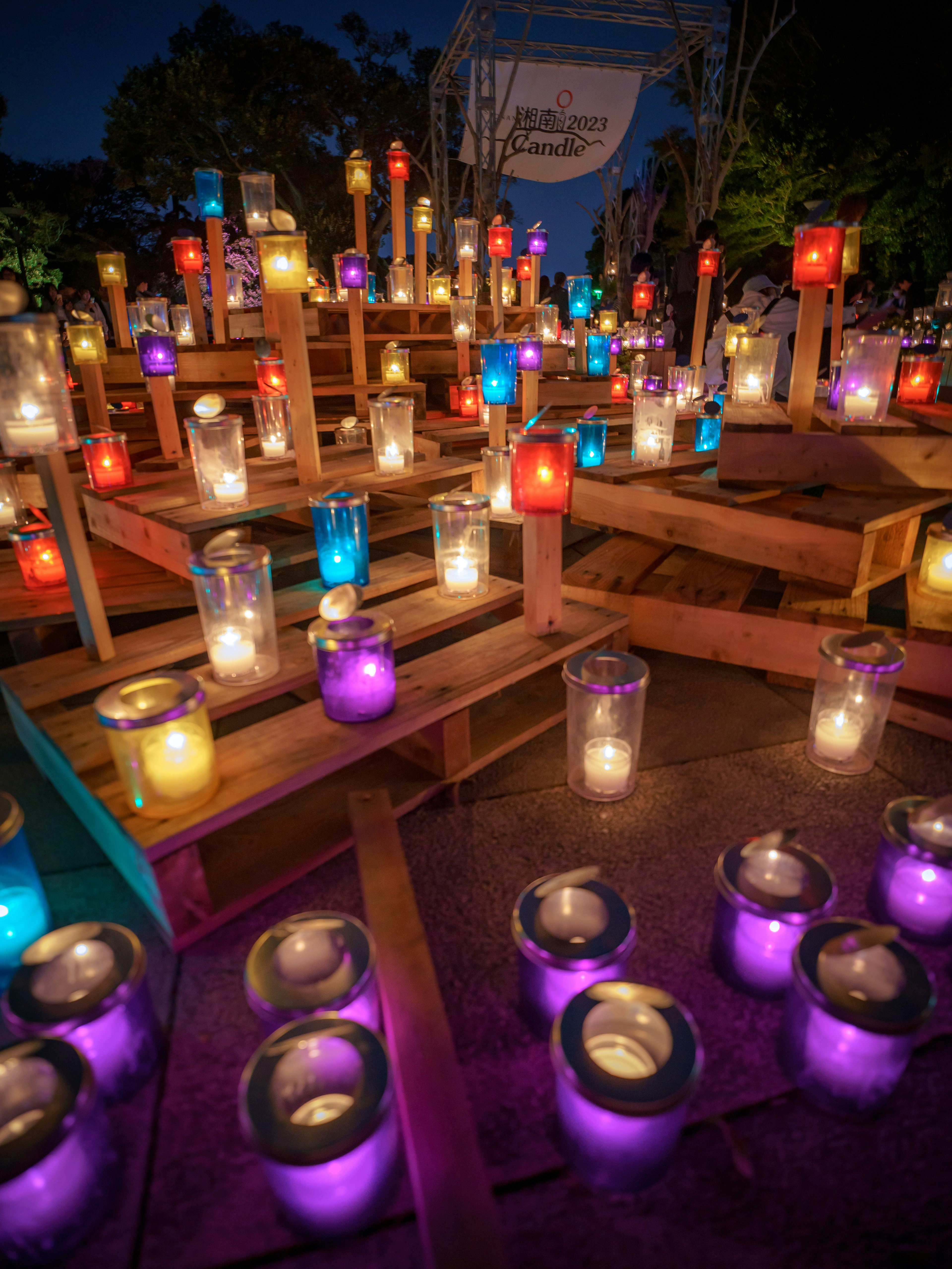 Des bougies colorées illuminent une structure en bois la nuit