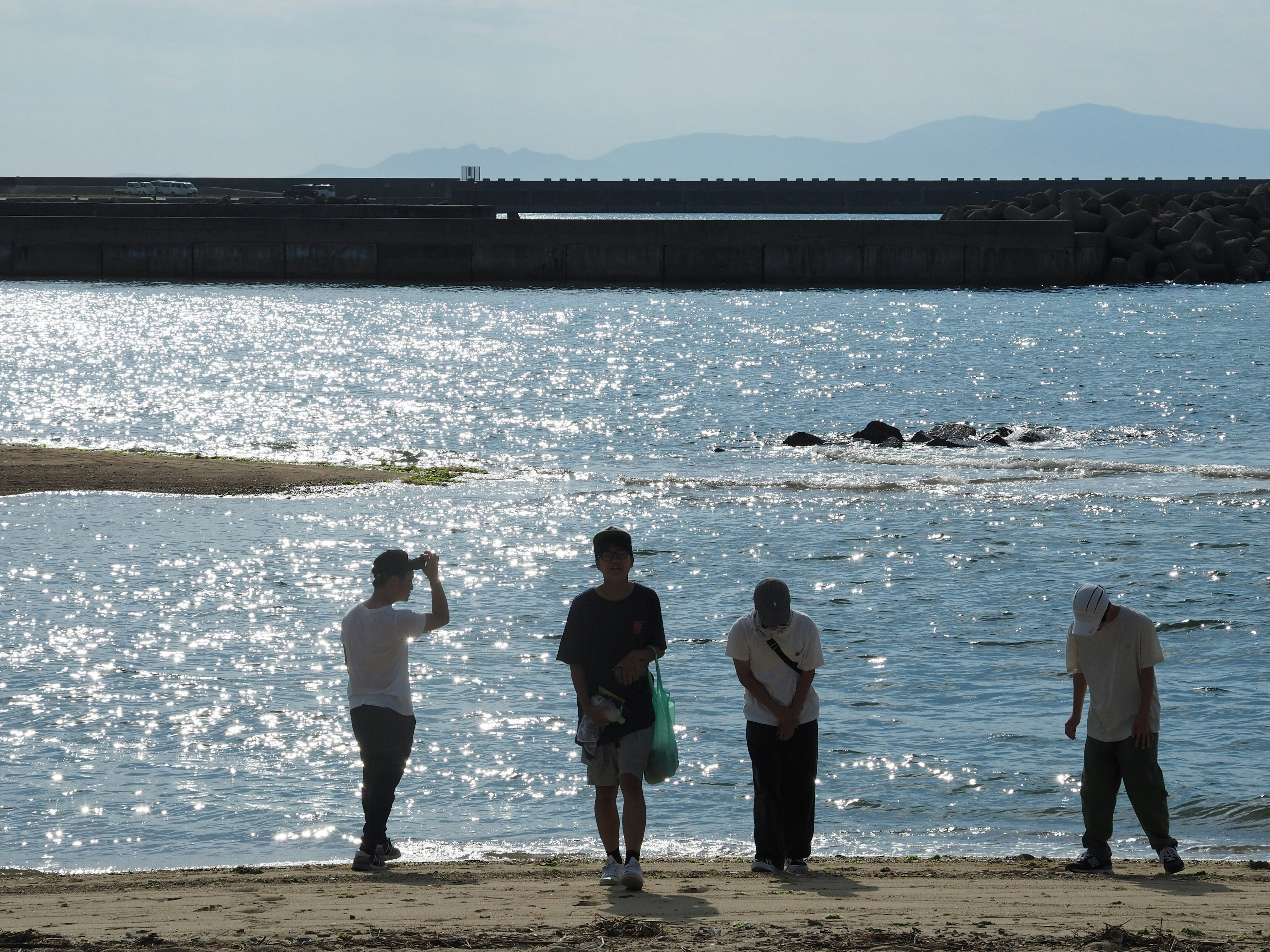 Siluetas de personas en la playa con agua brillante