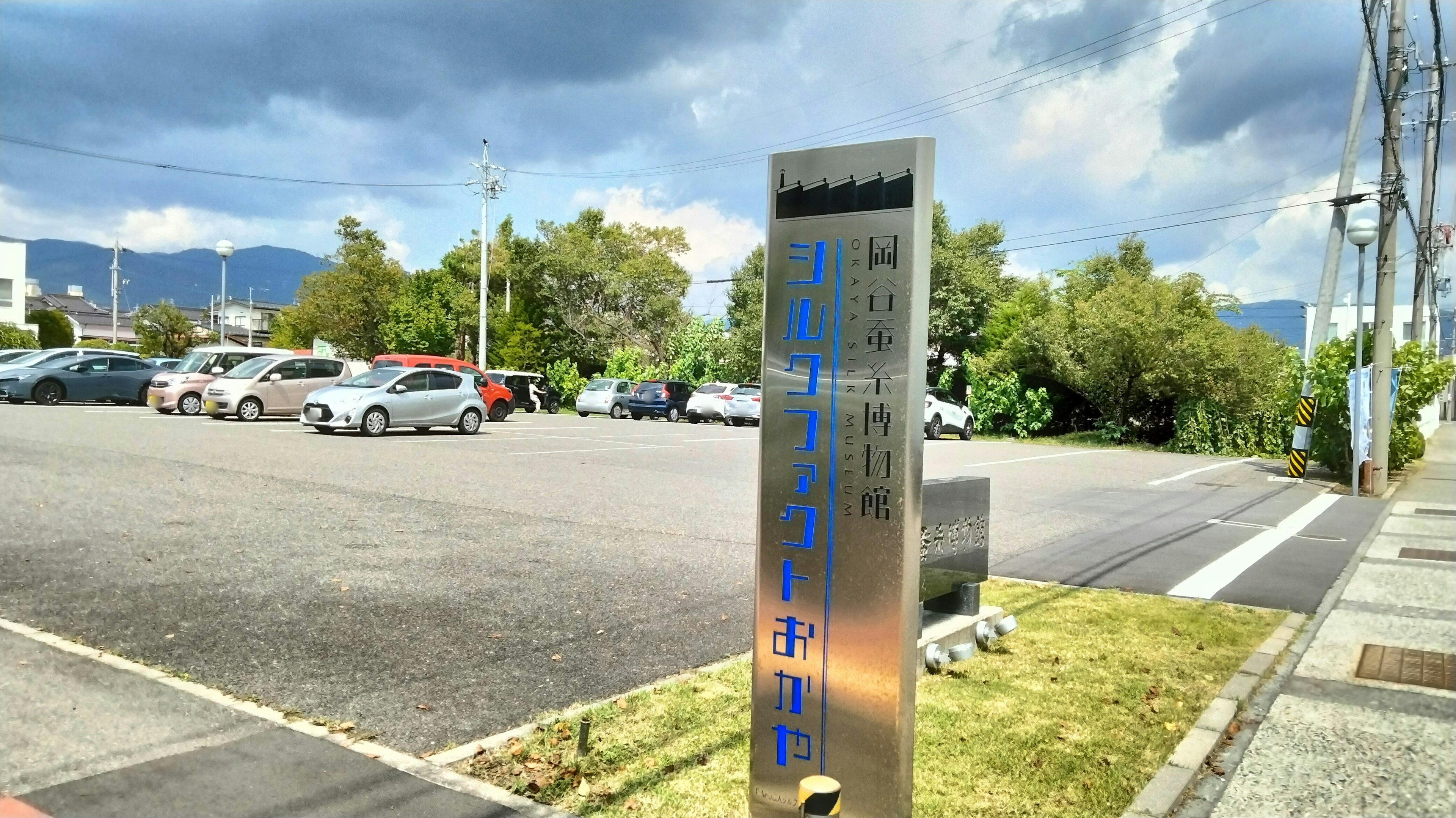 Parkplatzschild mit umgebender Begrünung und bewölktem Himmel