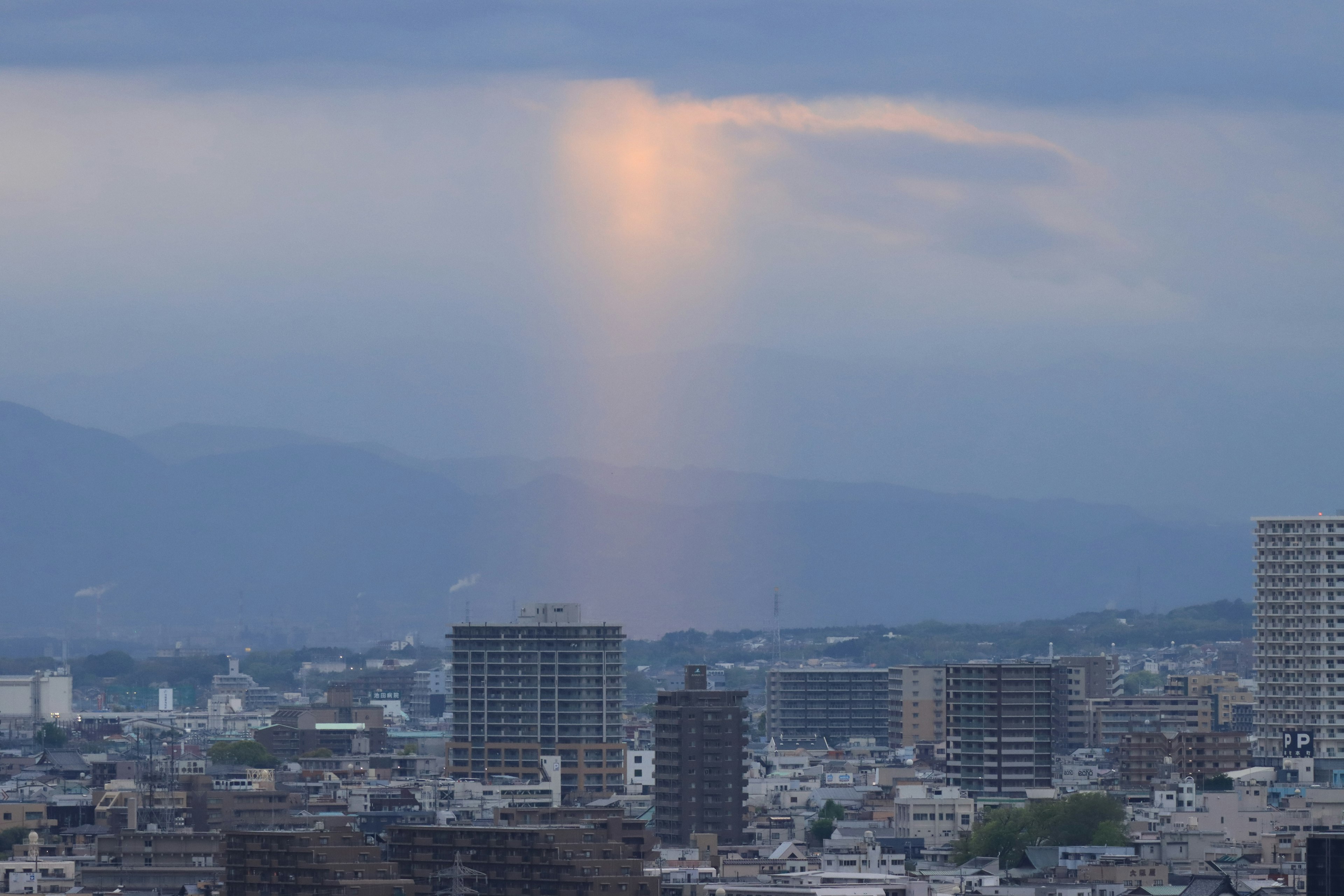 都市の上に現れる光の柱と雲の景色