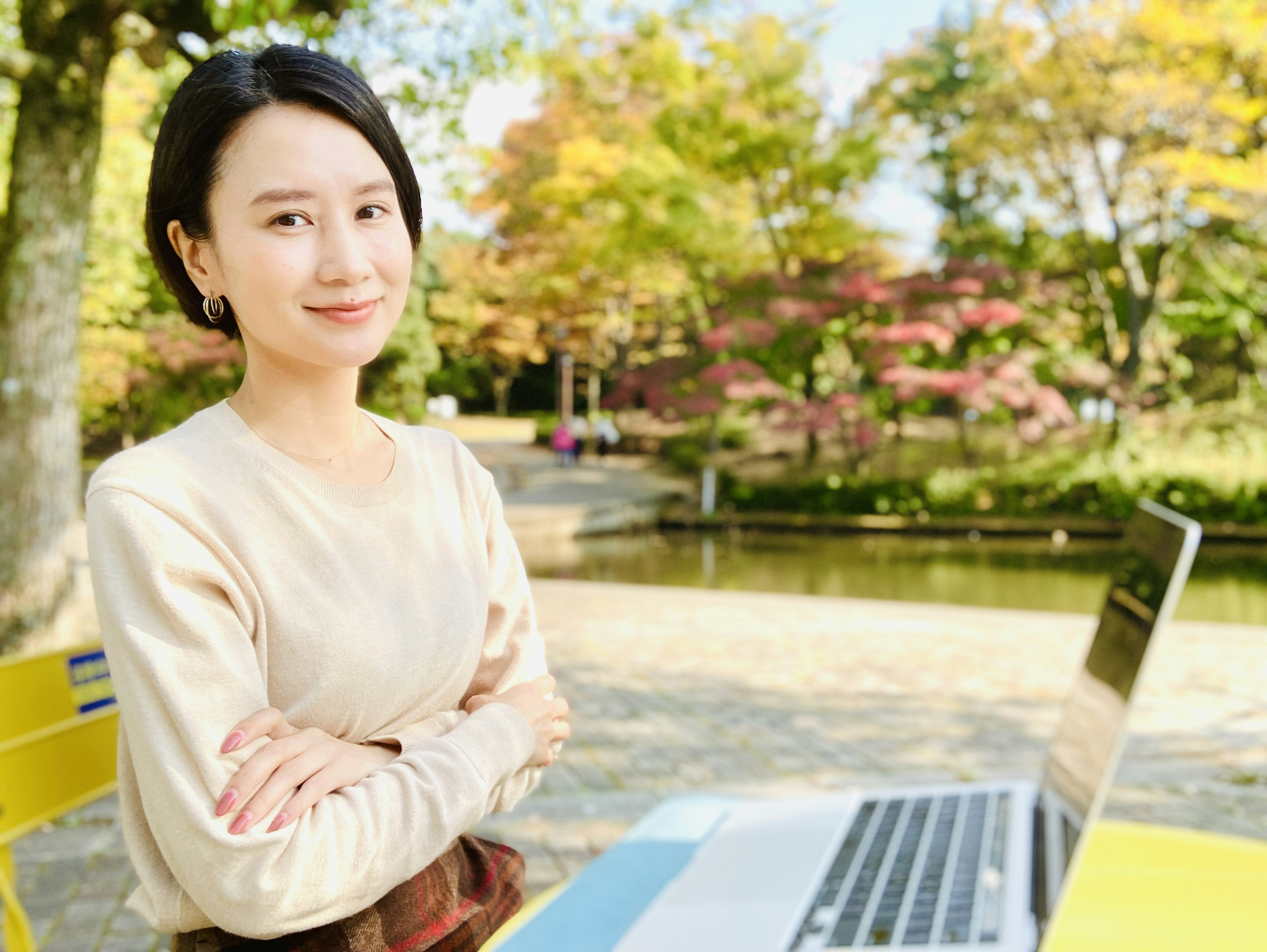 在公園使用筆記型電腦的女性肖像在秋季風景中微笑