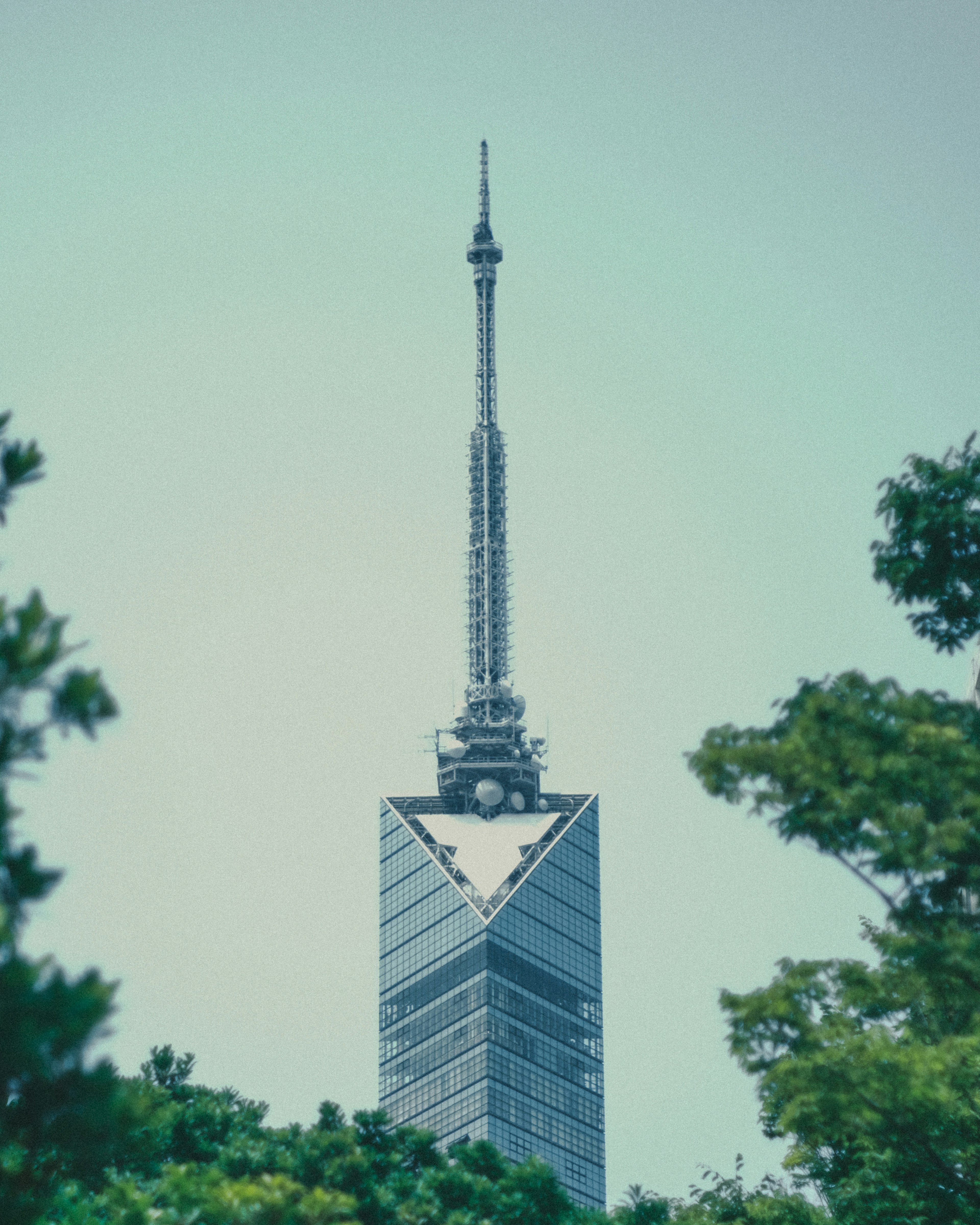 La torre Tokyo Skytree si erge contro un cielo blu chiaro circondata da alberi verdi