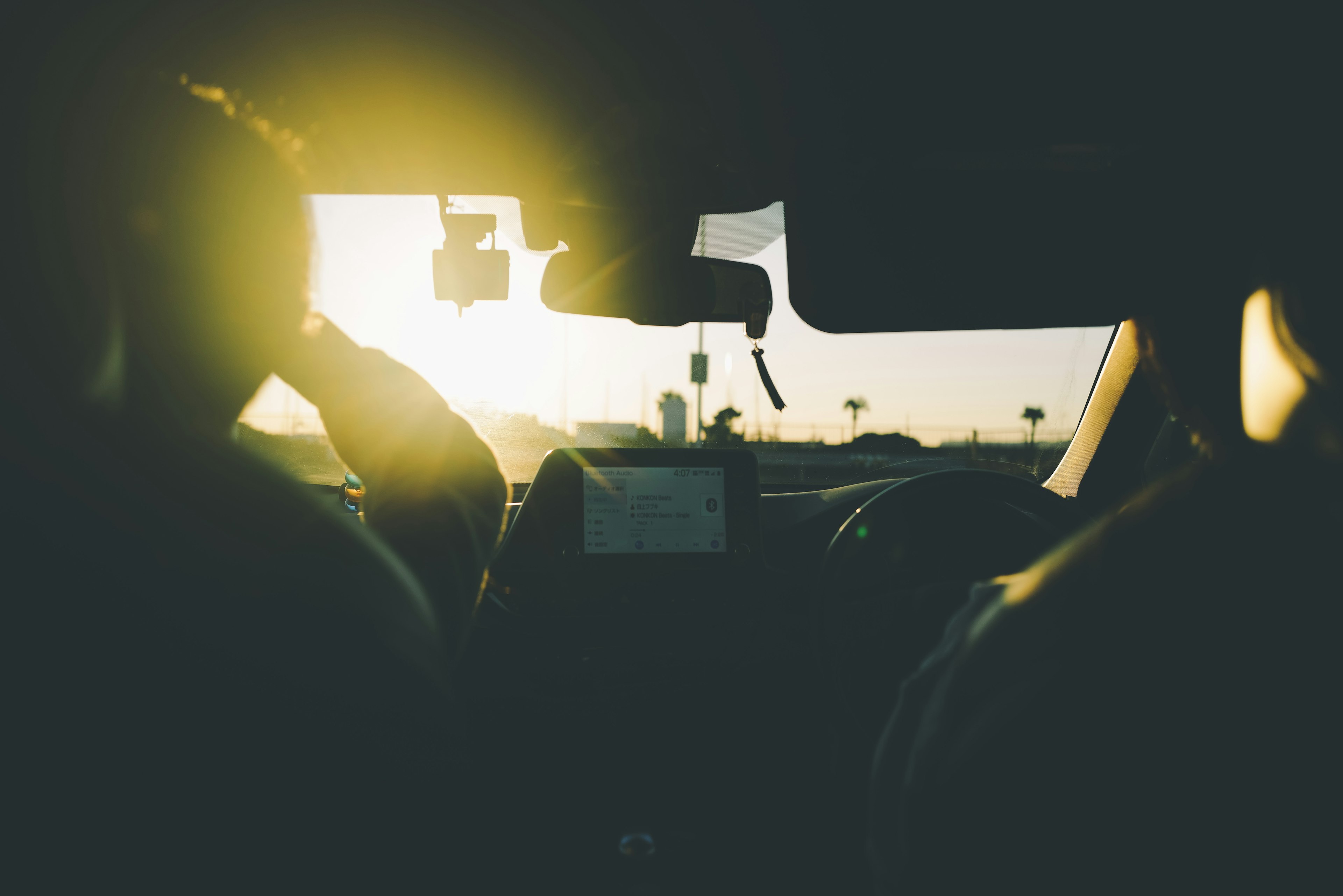 Zwei Personen in einem Auto mit Sonnenuntergang im Hintergrund