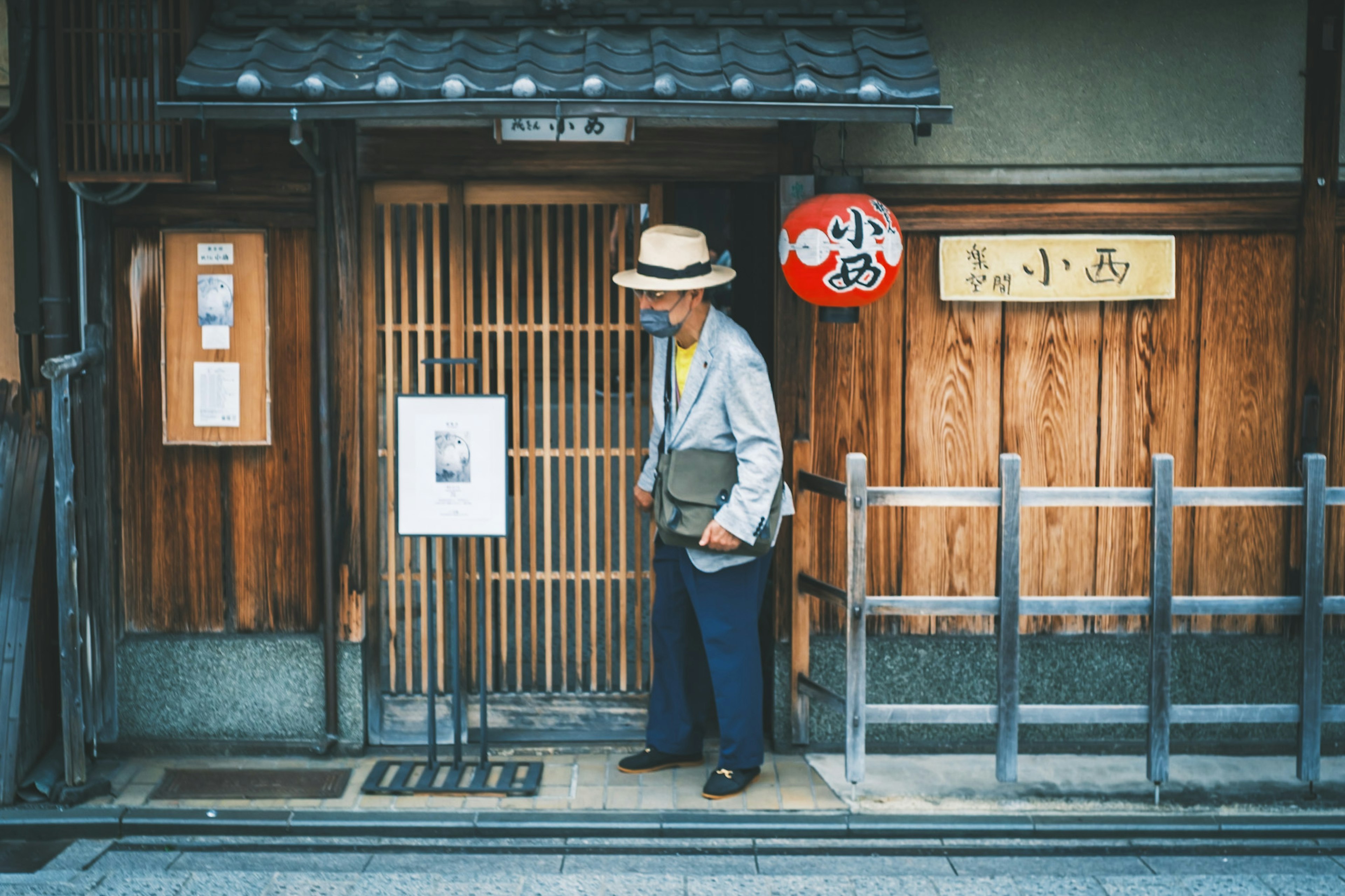 伝統的な日本の商店の前に立つ男性と木製の扉