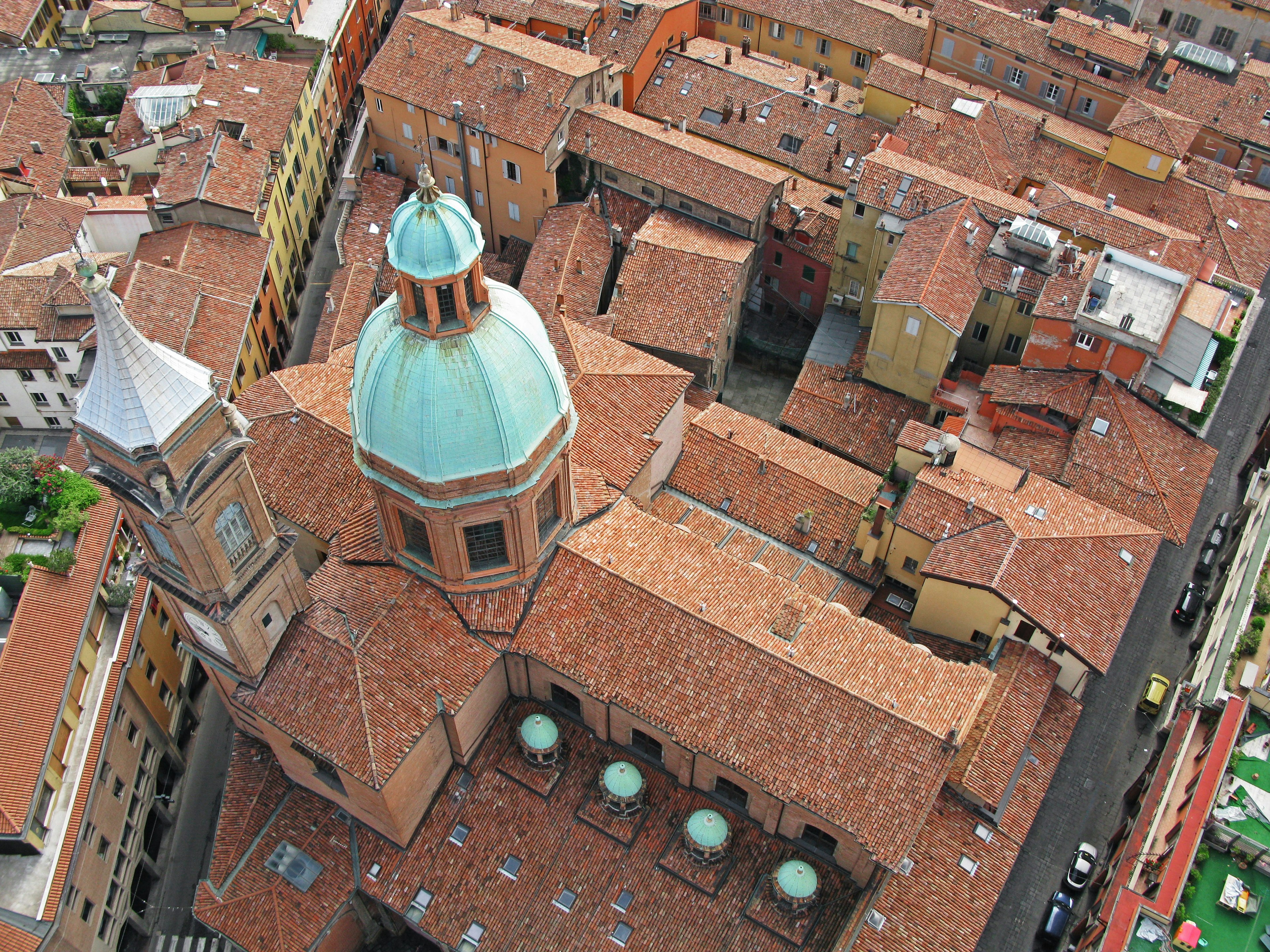 Aerial view of Bologna showcasing a church dome and surrounding red rooftops