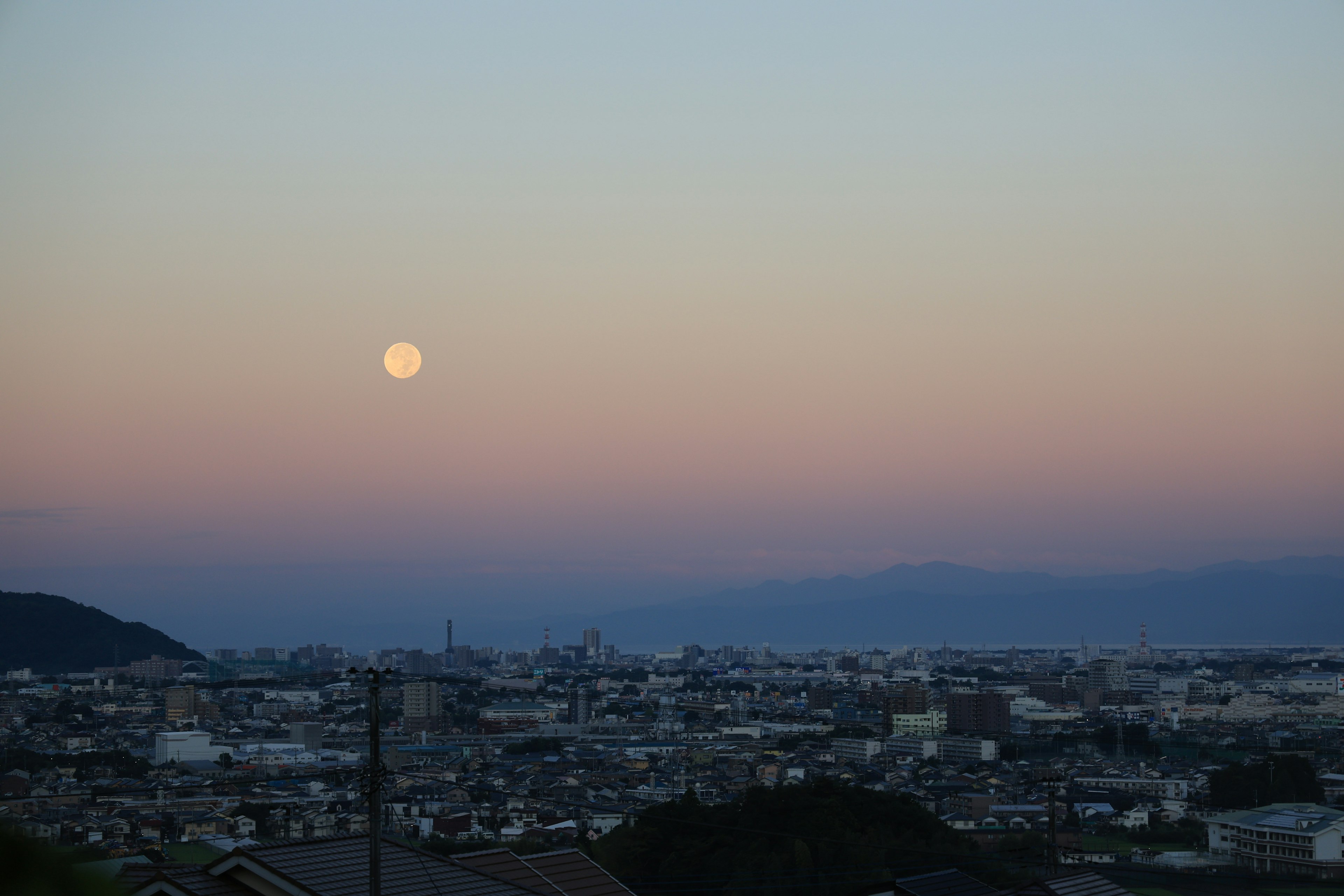 Pleine lune dans le ciel du soir au-dessus d'un paysage urbain