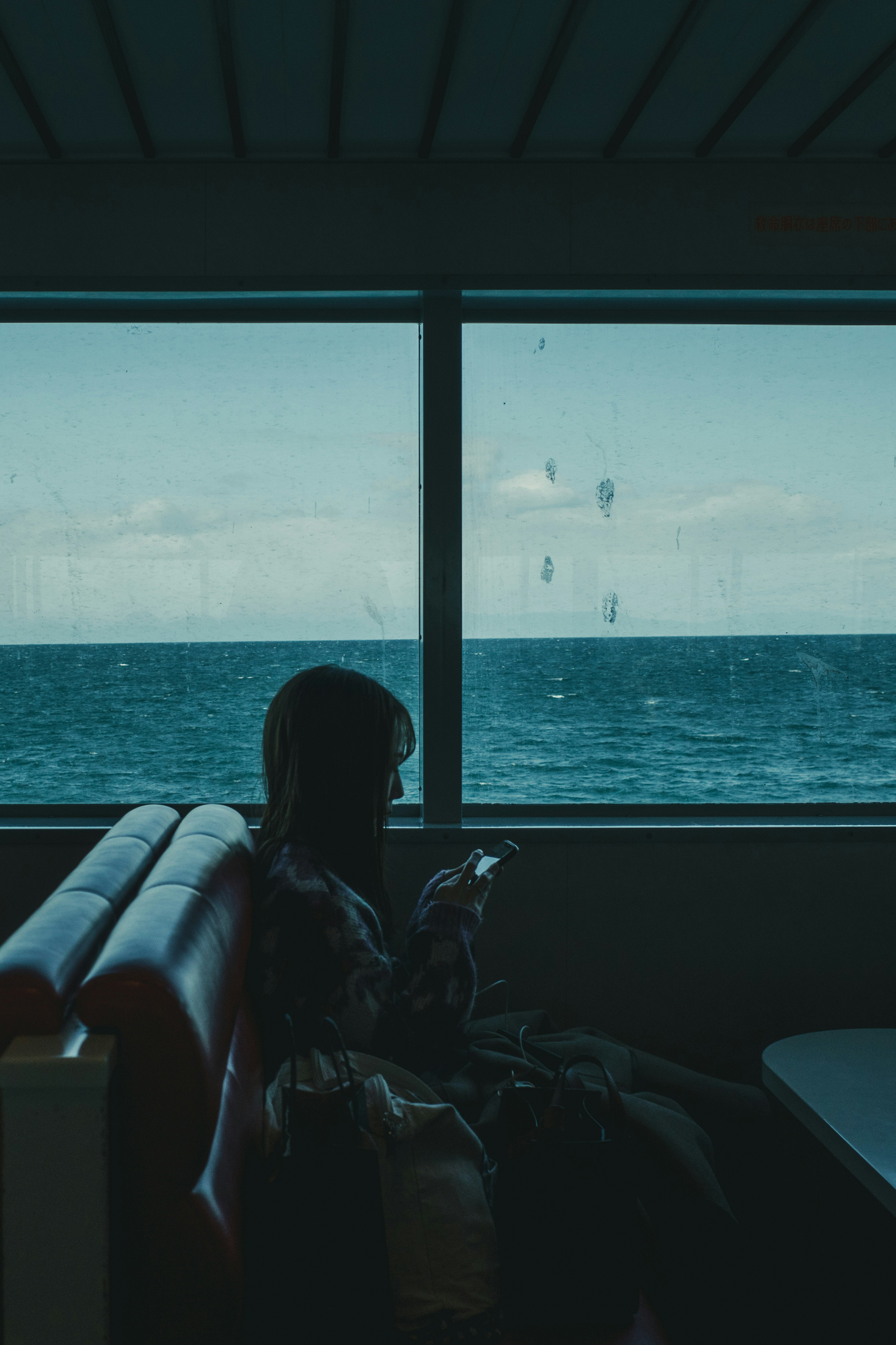 Silhouette of a person sitting by a window with ocean view