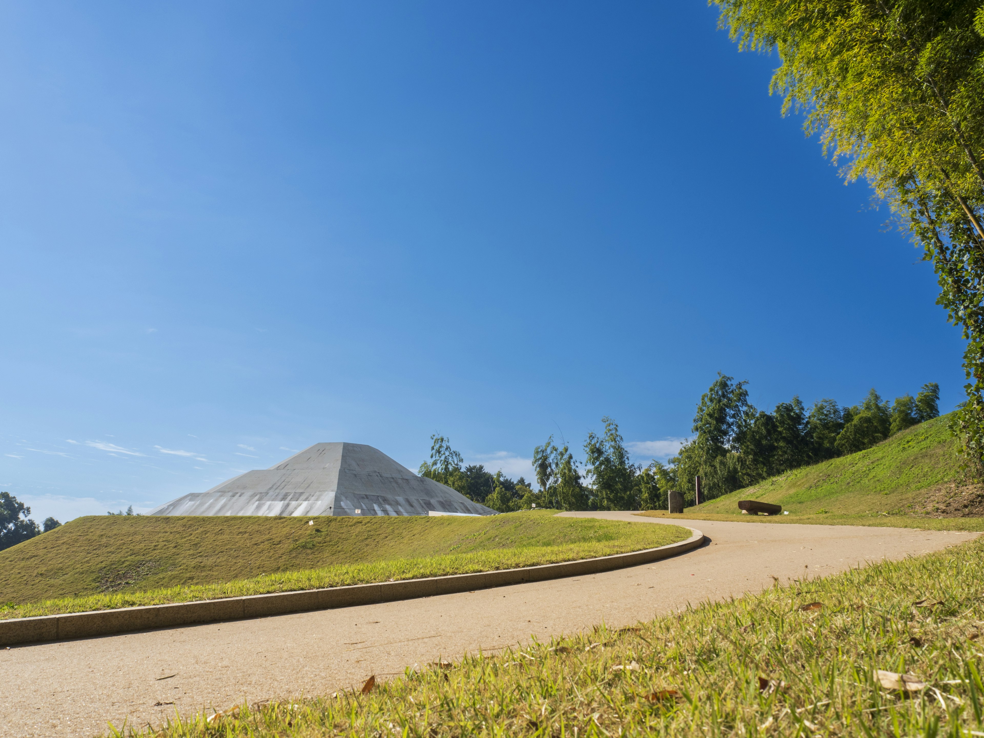 Curved pathway through green hills under a clear blue sky