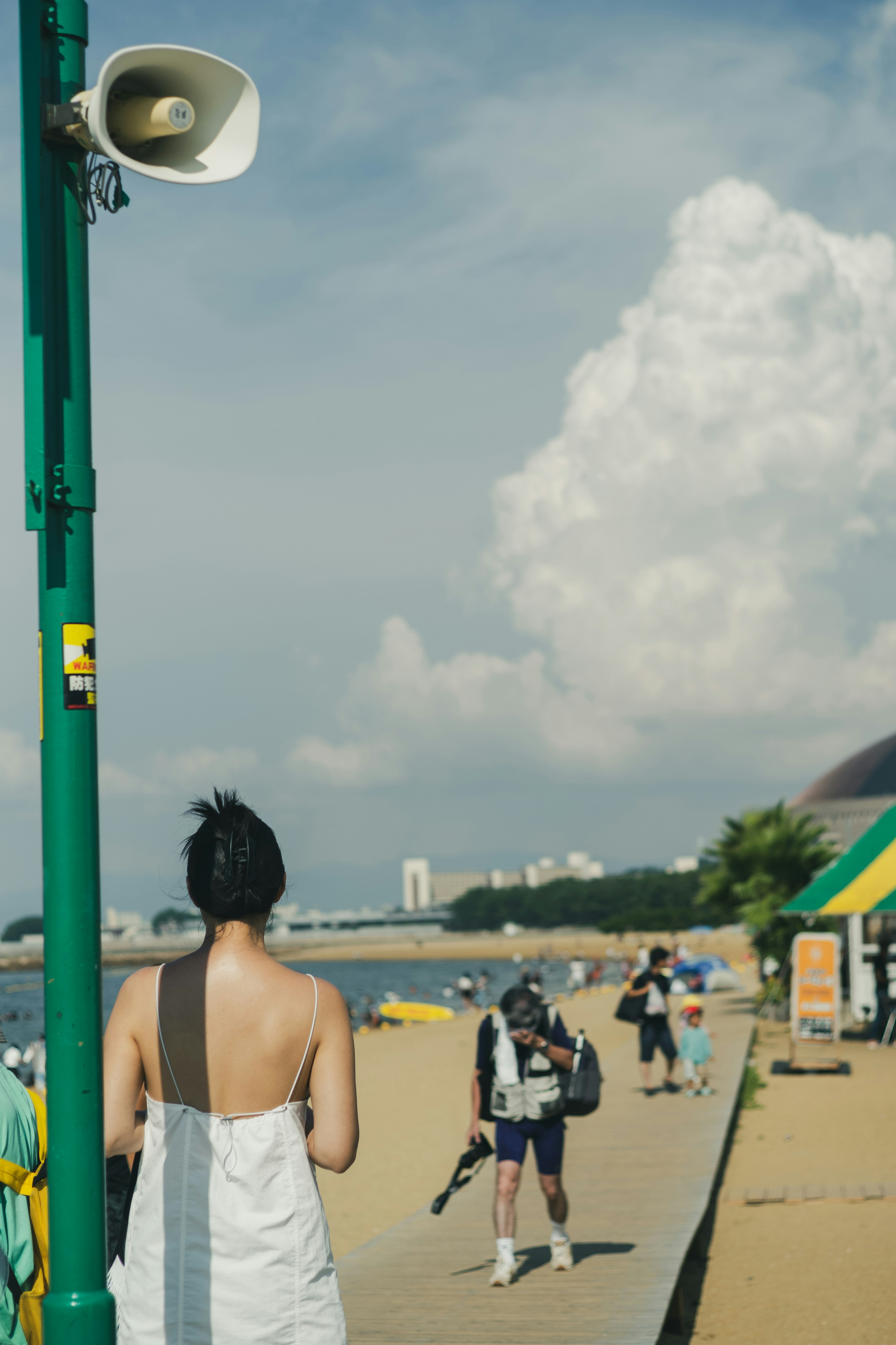 ビーチで背を向けて立っている女性と青い空の雲