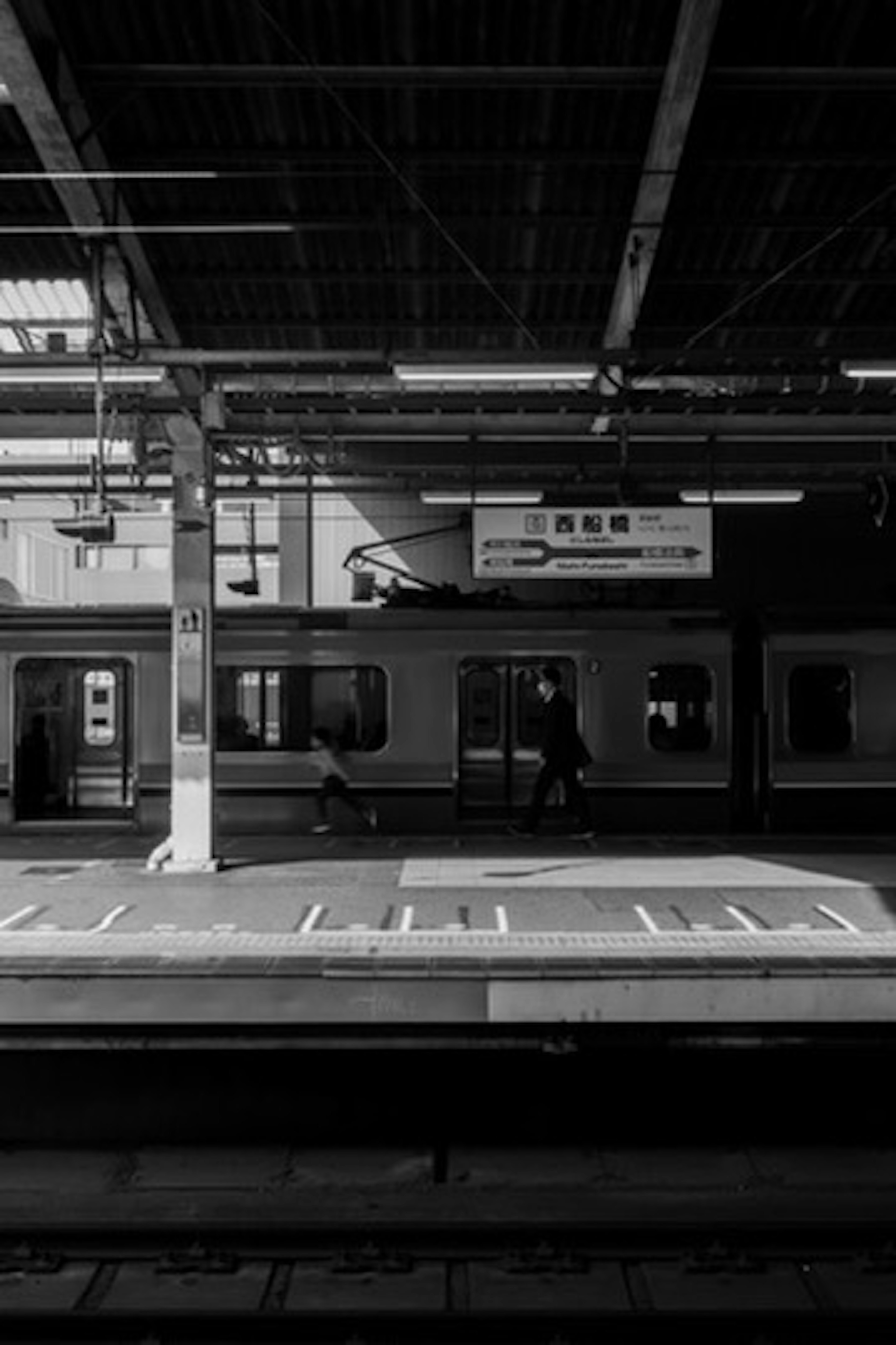 Plateforme en noir et blanc avec des personnes et un train à la gare