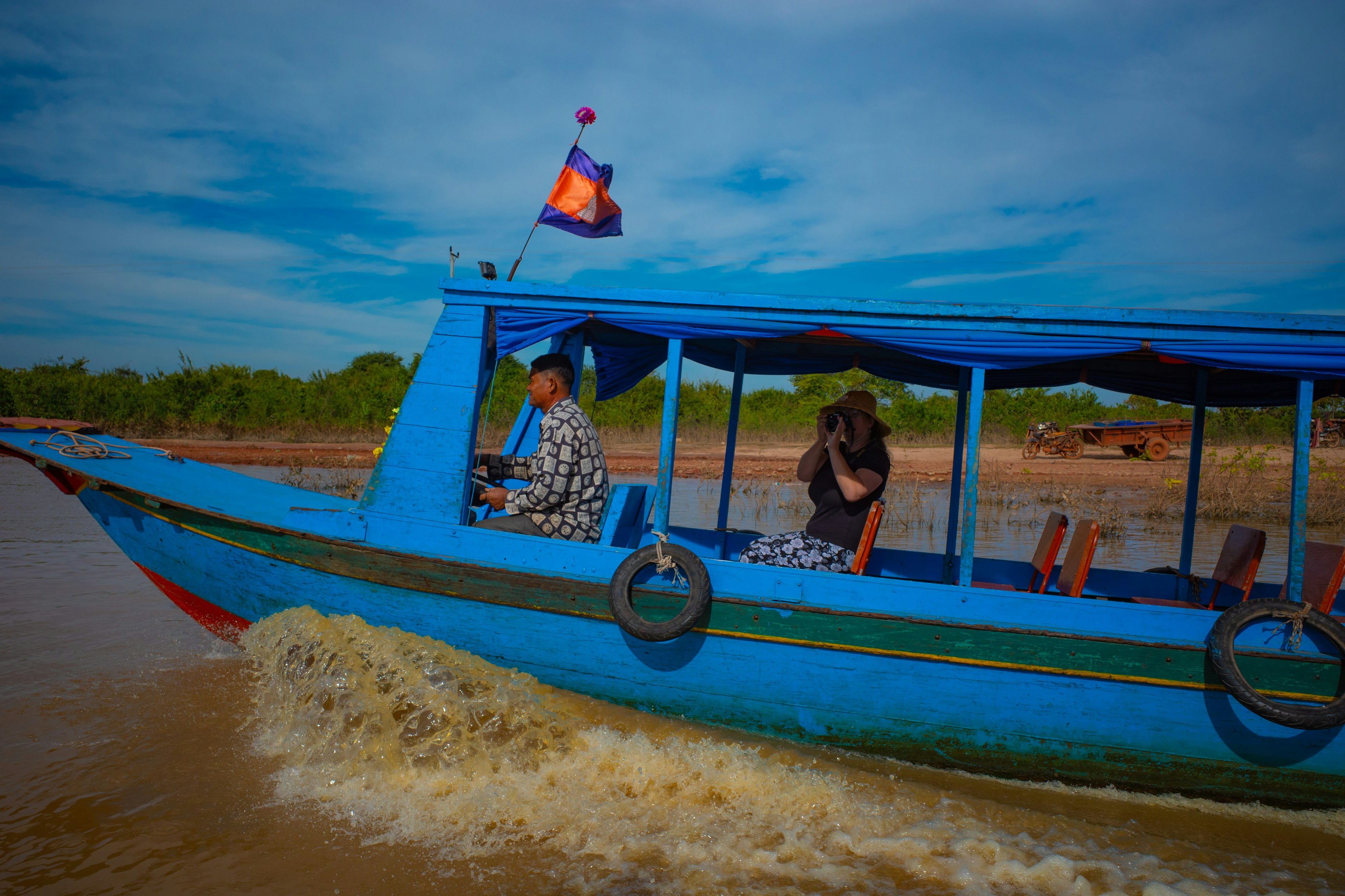 คนสองคนบนเรือสีน้ำเงินที่สร้างน้ำกระเซ็นในน้ำ