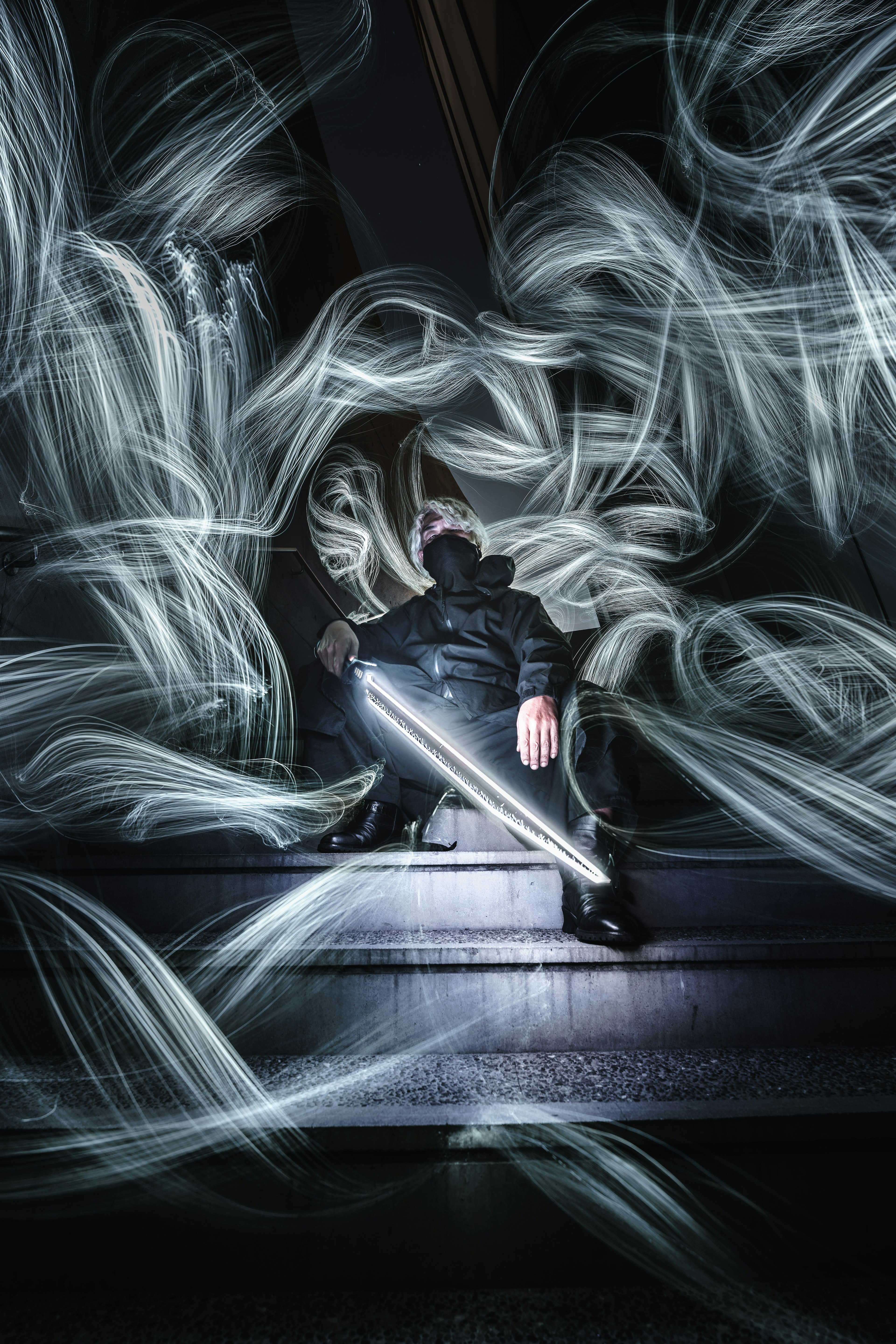 Person sitting in a dark setting surrounded by ethereal light trails