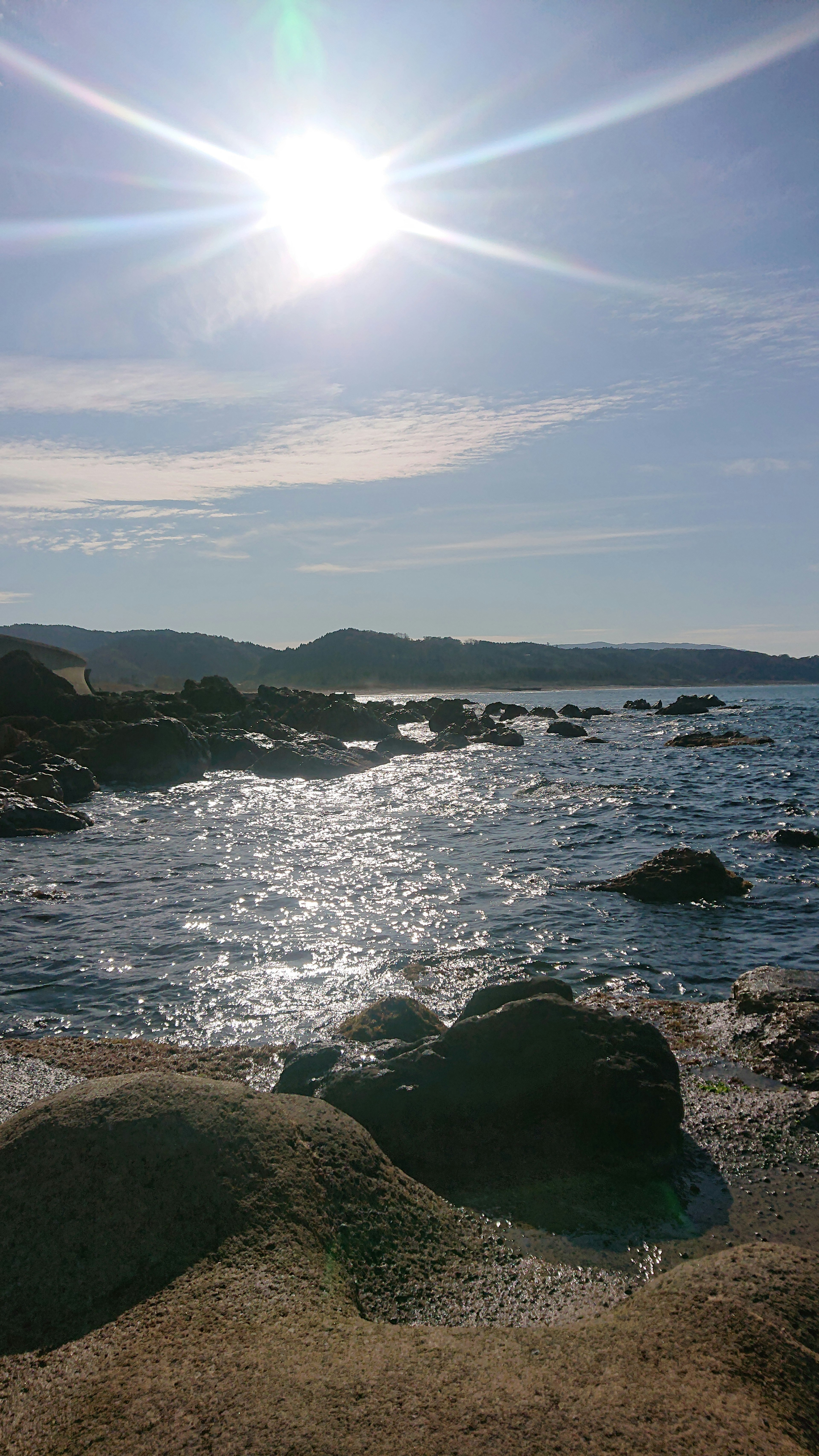 Hermoso paisaje costero con rocas y sol brillante sobre el mar