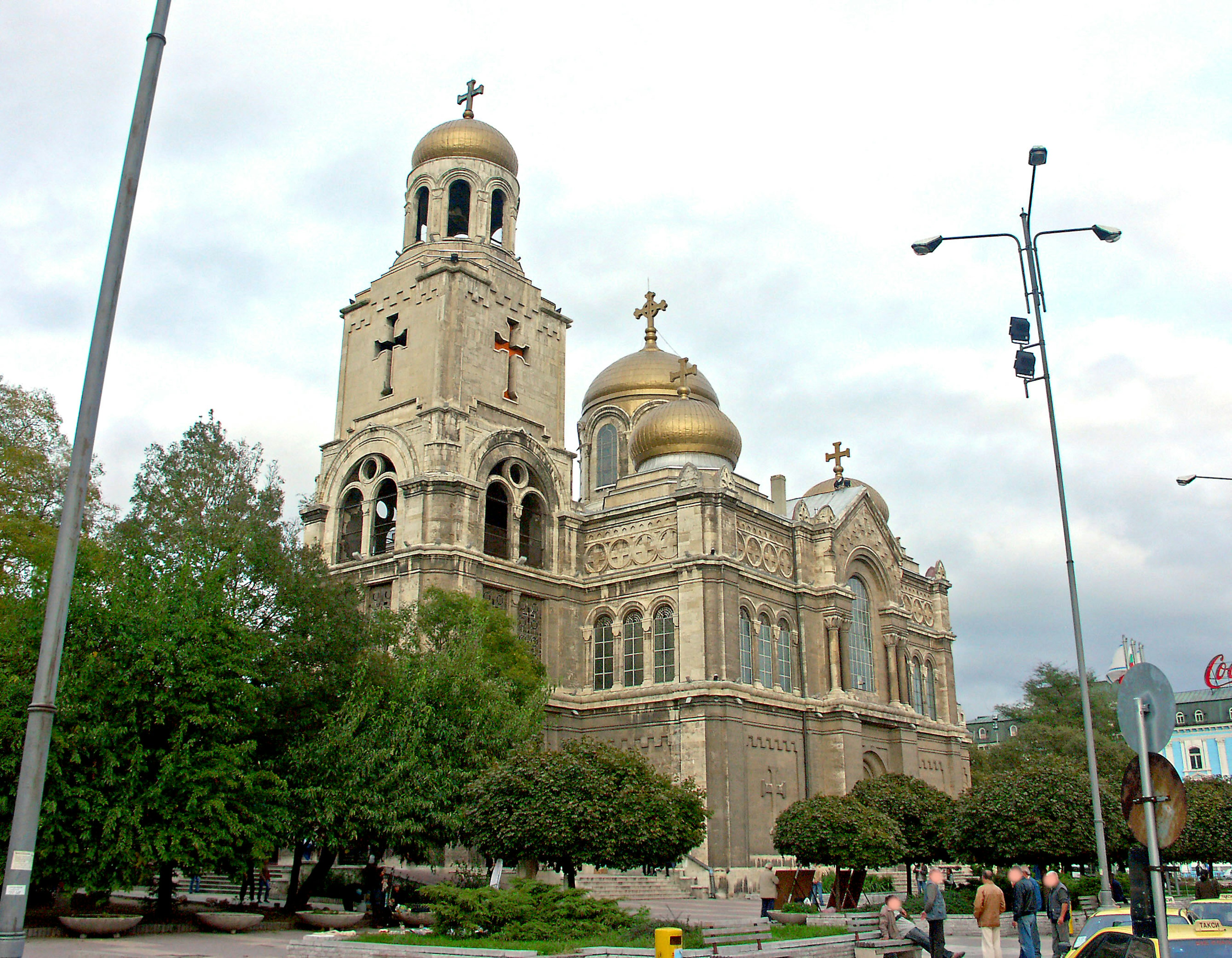 Exterior view of a church with golden domes and surrounding greenery