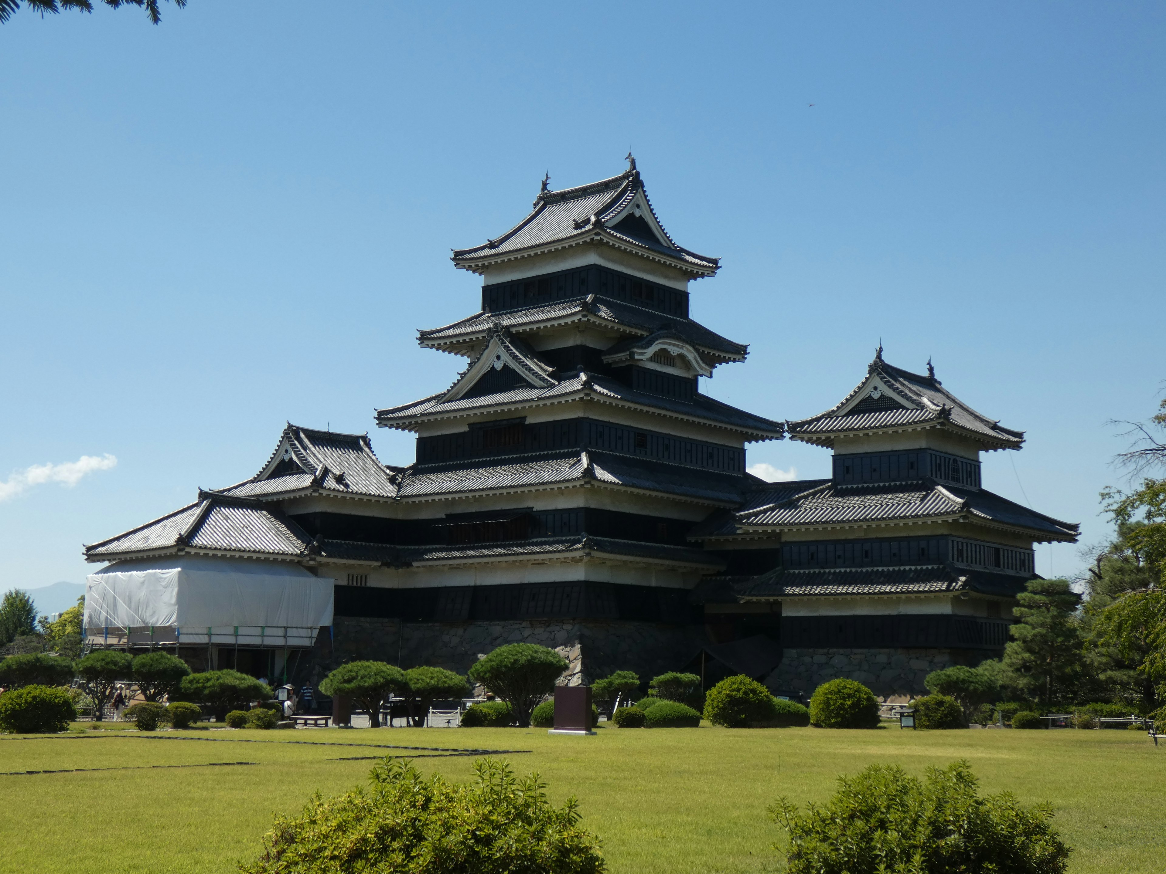 Hermosa vista exterior del castillo de Matsumoto con cielo azul y jardines verdes