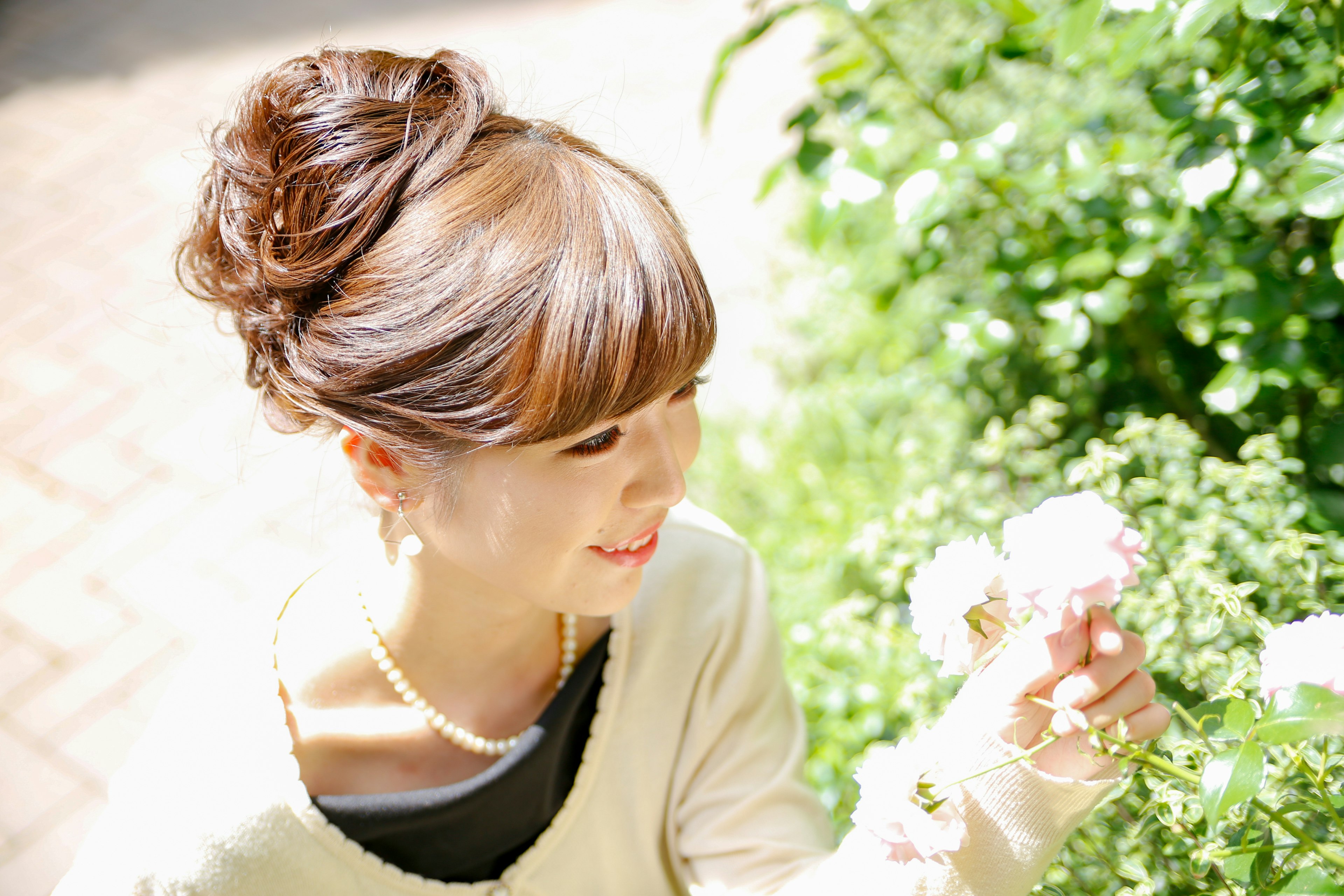 Woman smiling while holding flowers in a lush green background enjoying nature's beauty