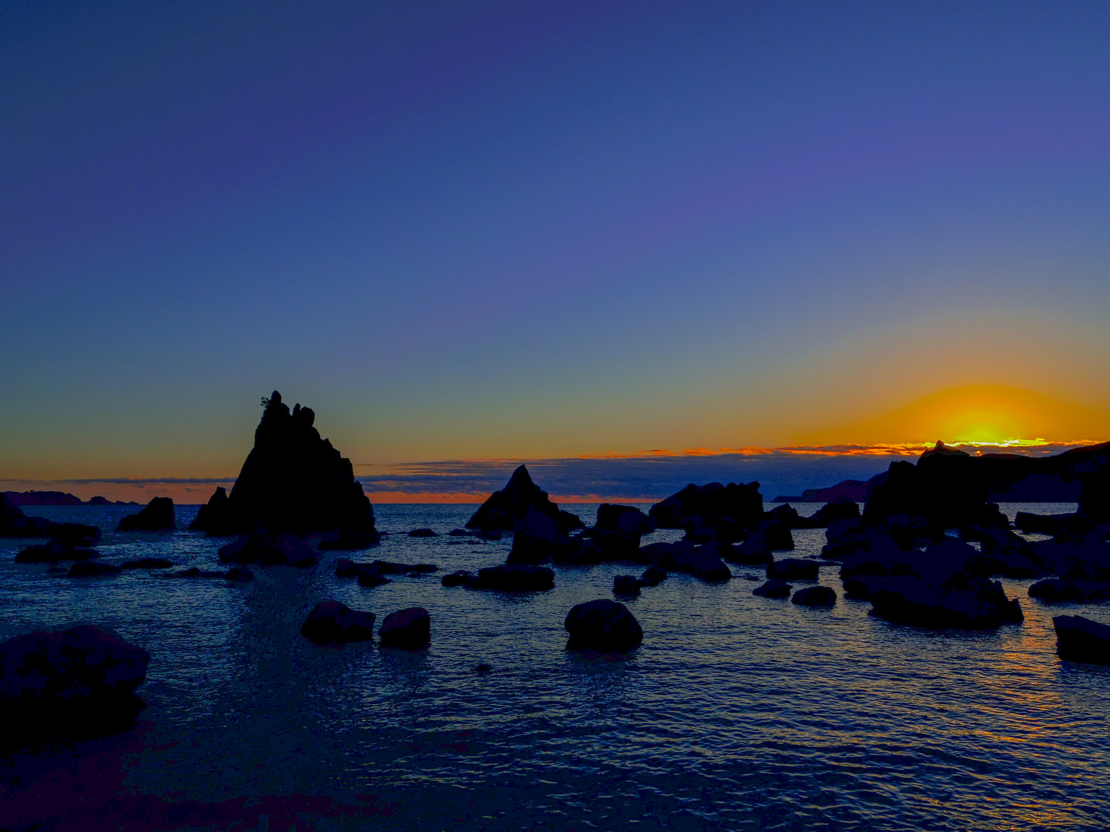 Impresionante atardecer sobre el océano con siluetas de rocas