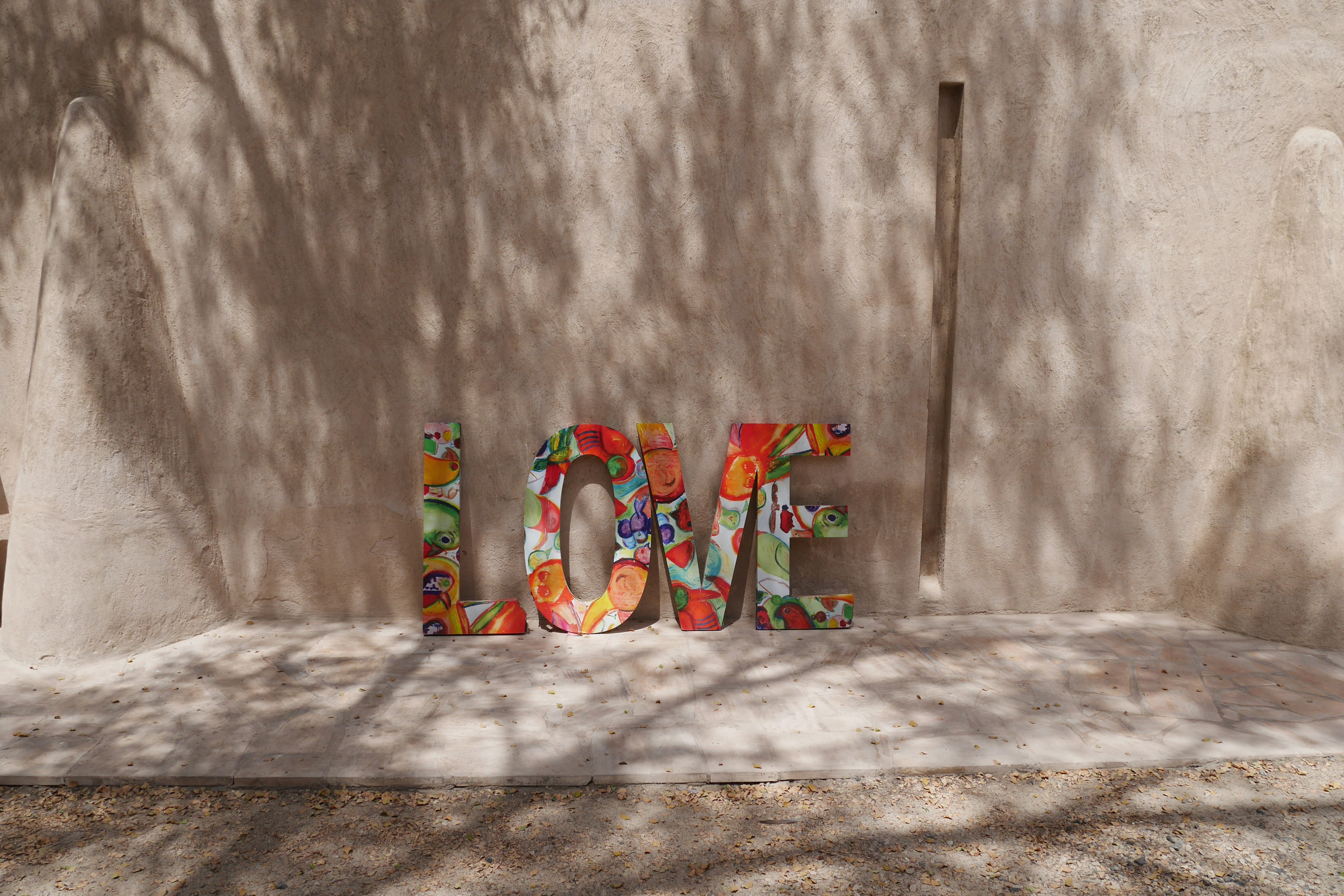 Bunte Blumenbuchstaben, die das Wort Liebe an einer strukturierten Wand bilden