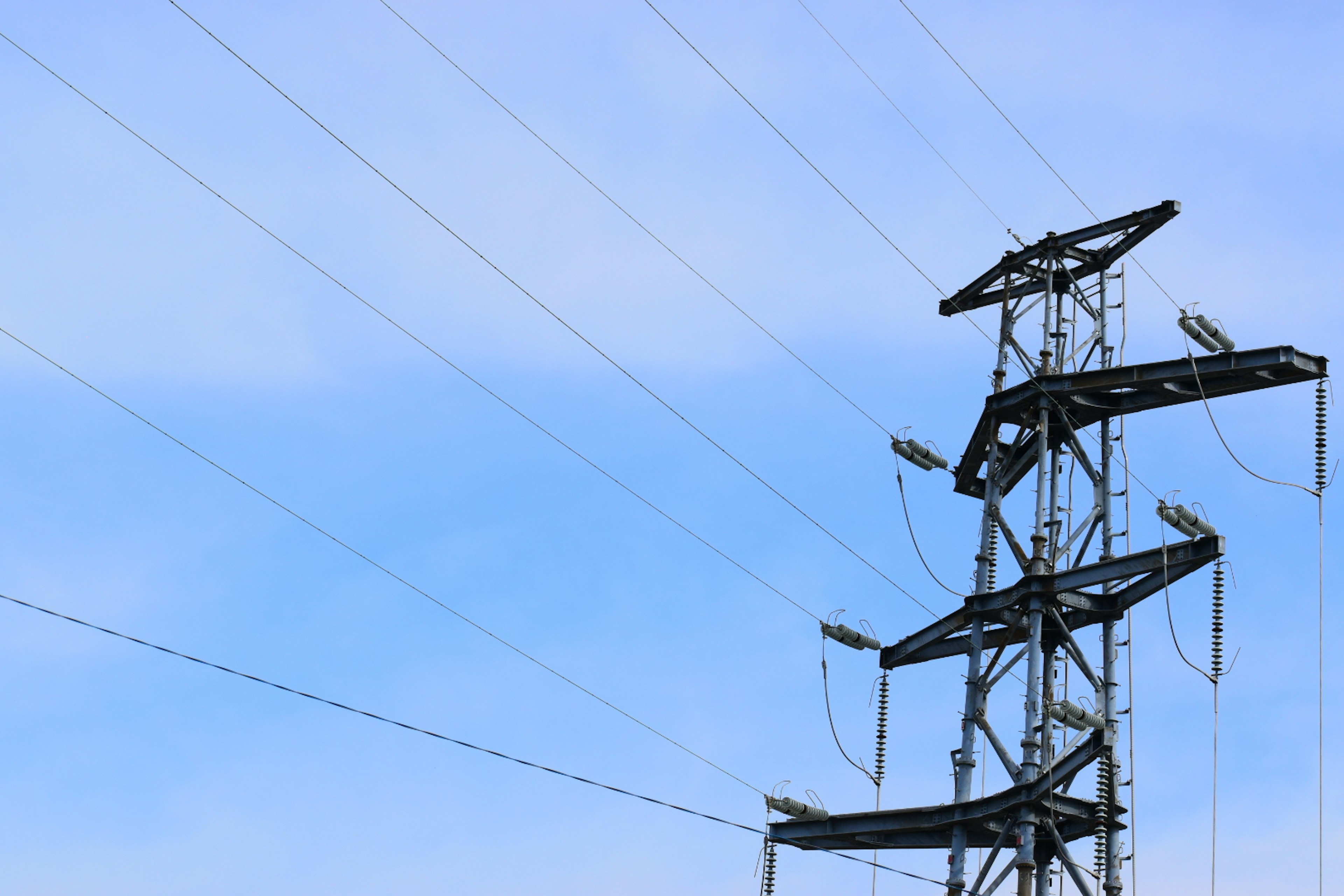 Strommast und Leitungen unter einem blauen Himmel