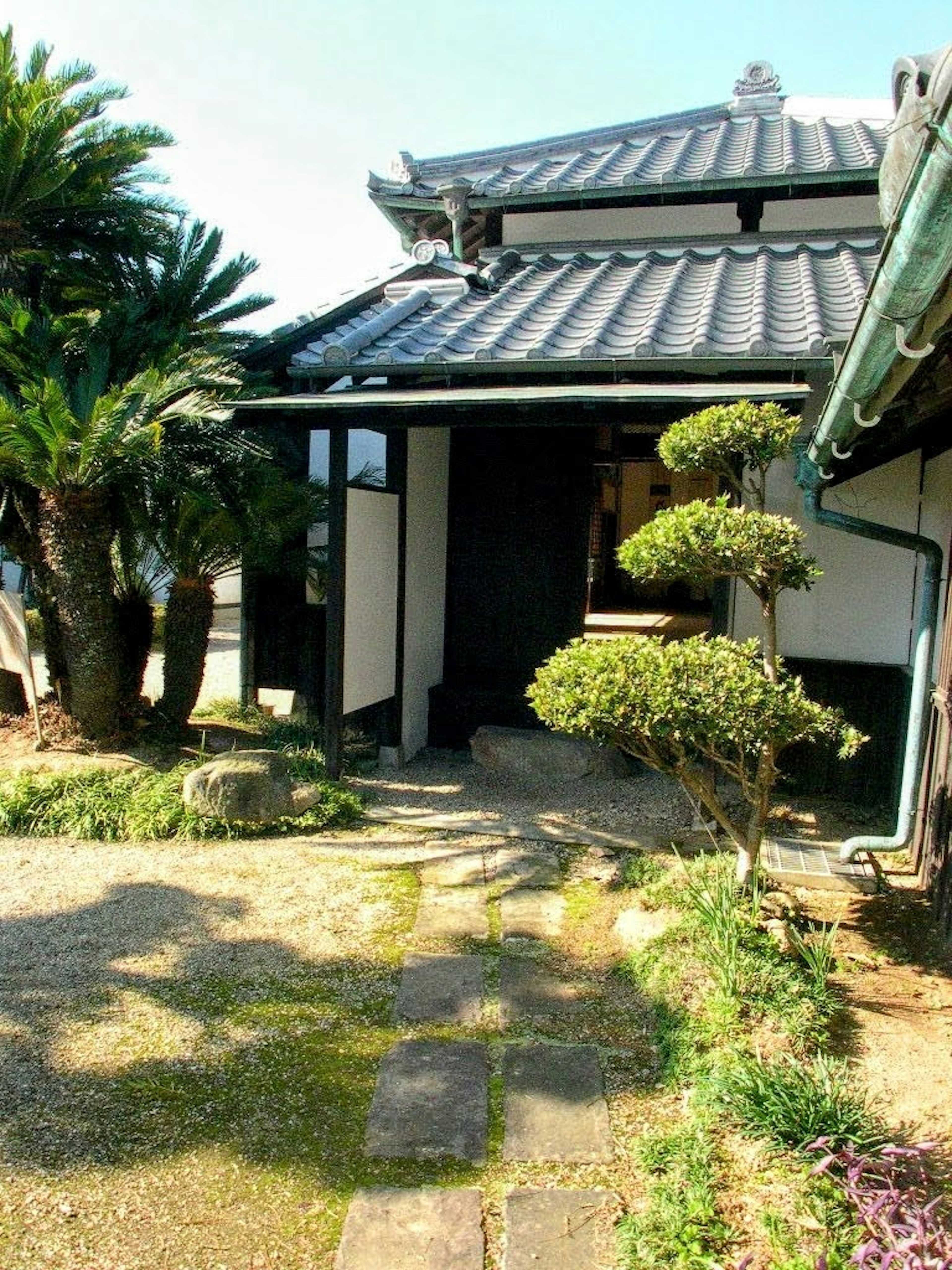 Traditional Japanese house with a garden featuring a tiled roof and manicured plants