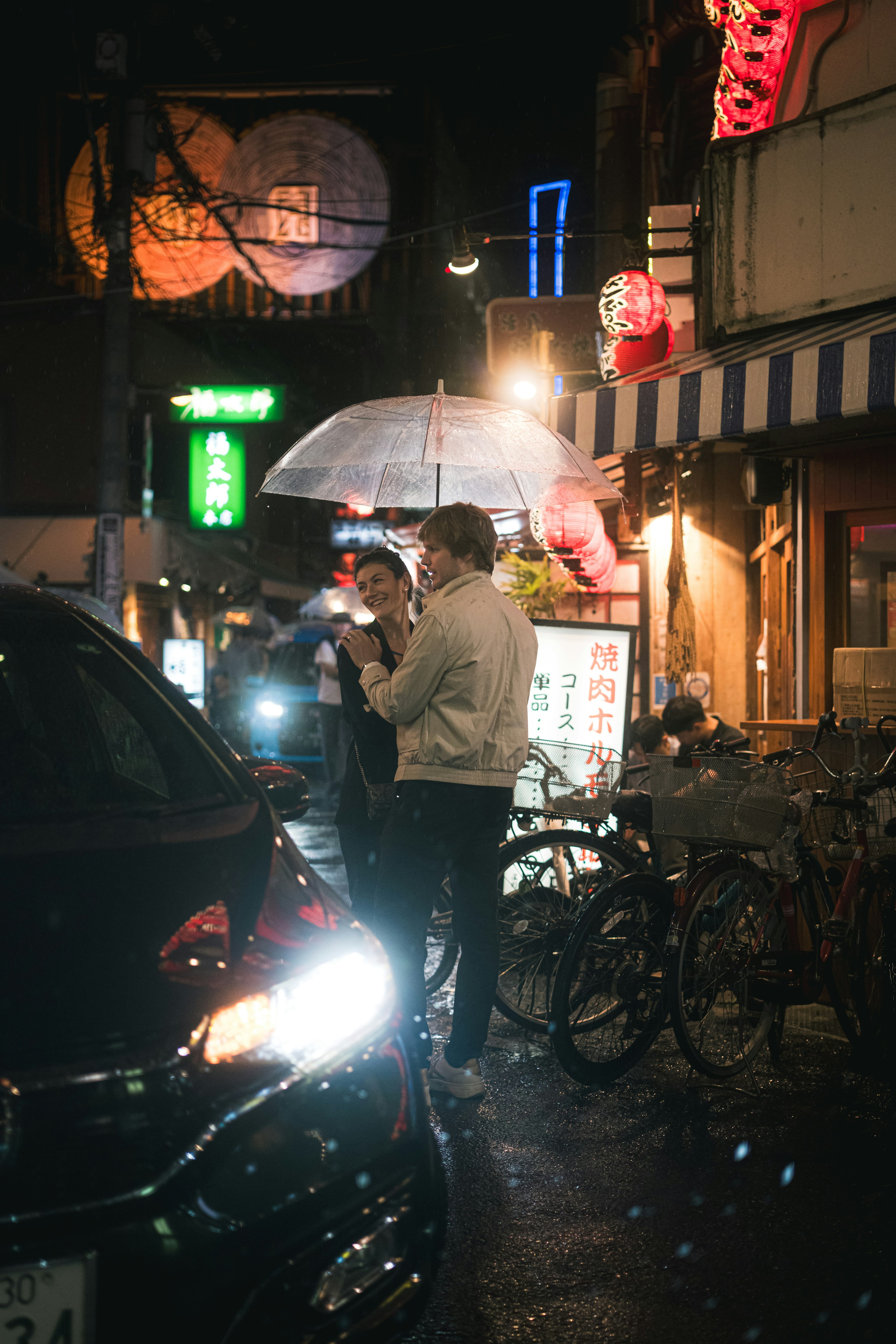 Night scene with two people under an umbrella and a car