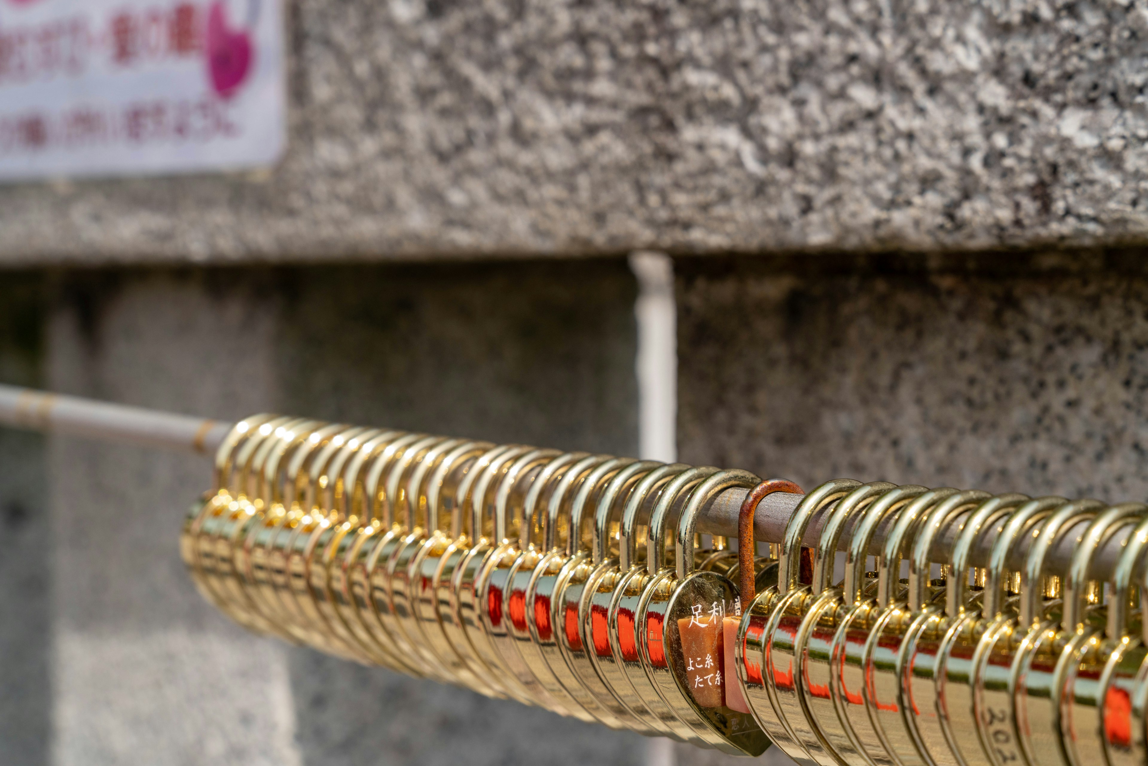 A close-up of golden padlocks arranged on a wire against a stone wall