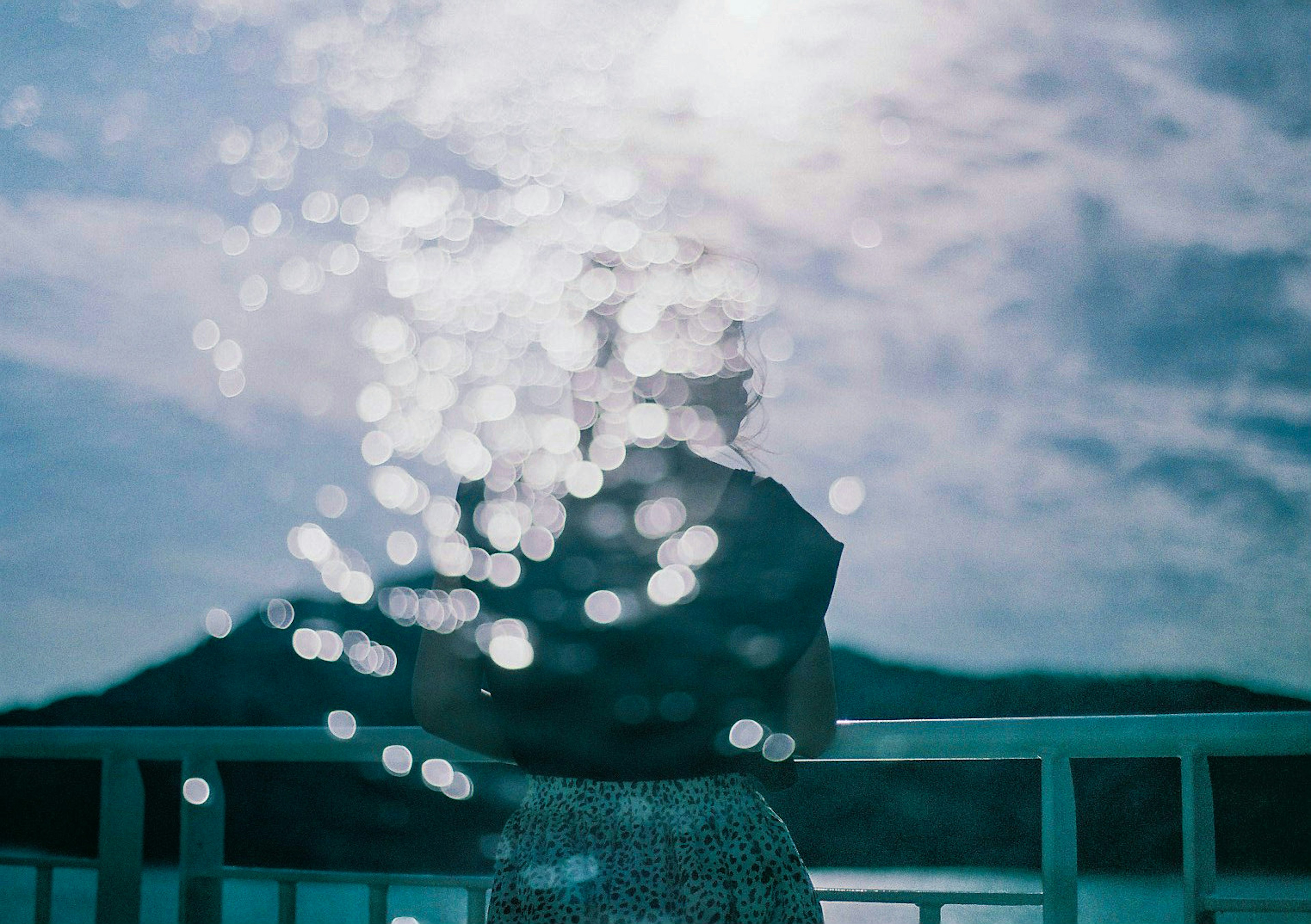 Silhouette of a woman with water reflections behind her blue sky and clouds in the background