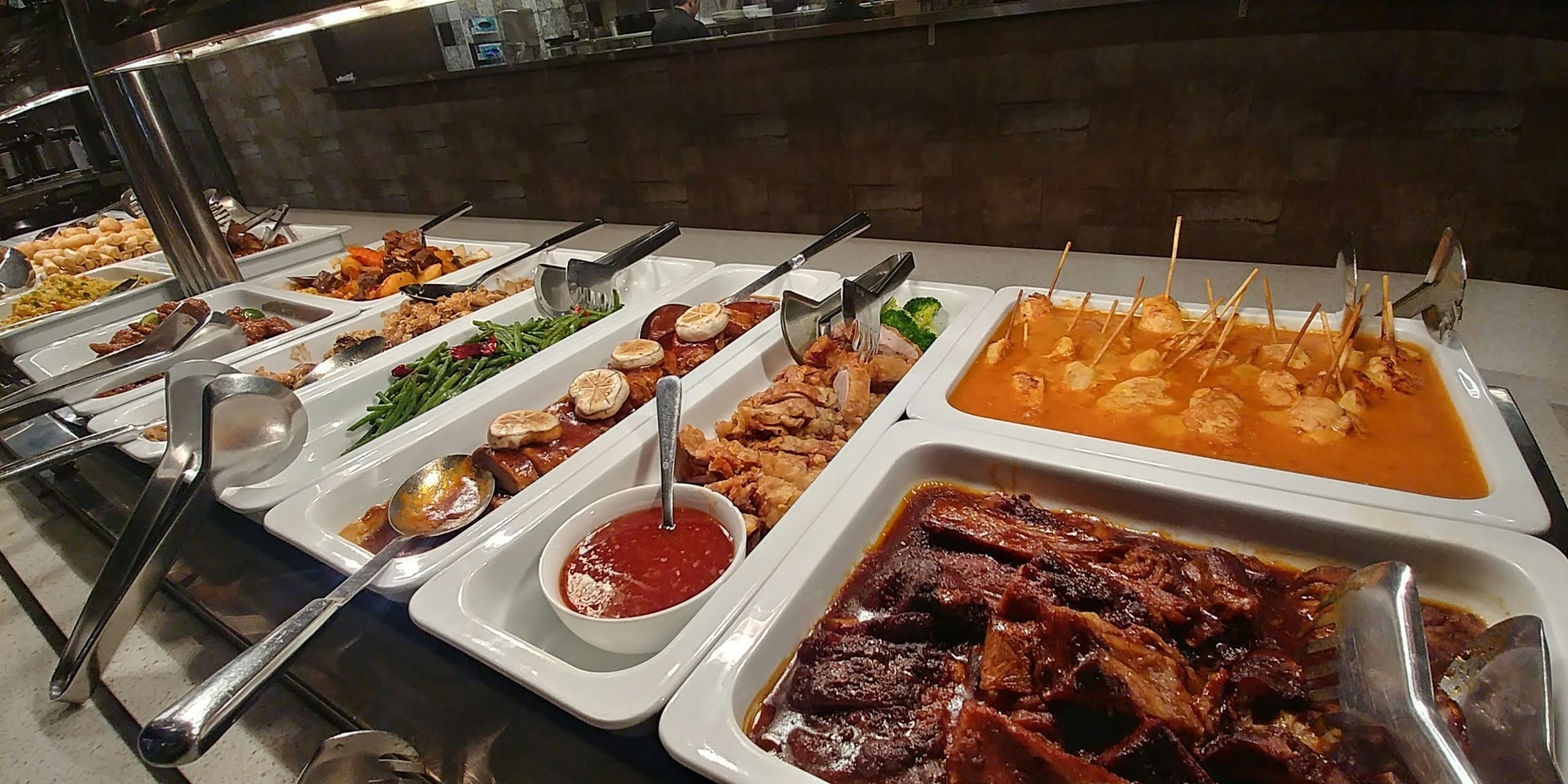 Long buffet table filled with various dishes including meats and sauces