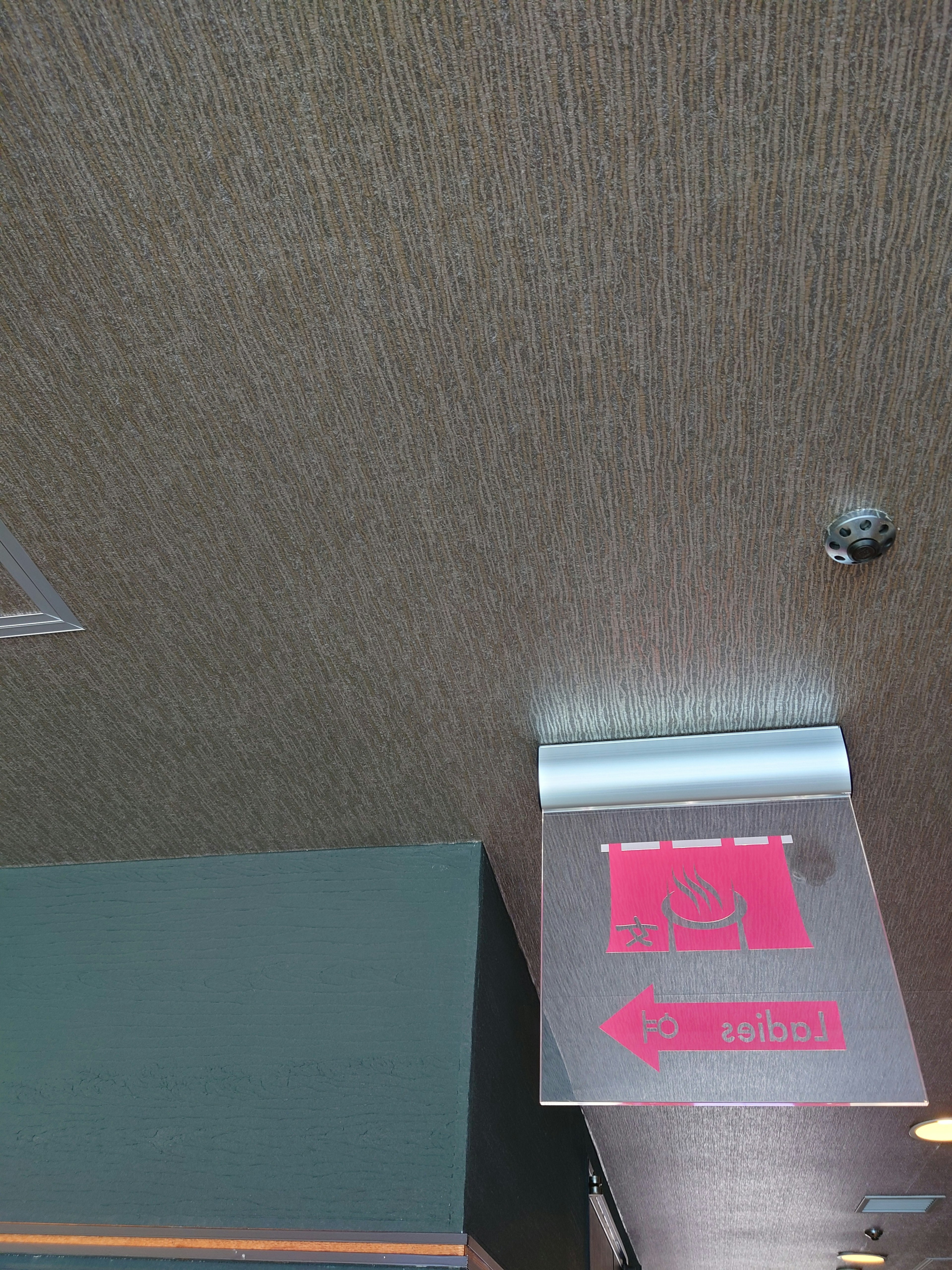 Wood-grain ceiling design with pink directional sign