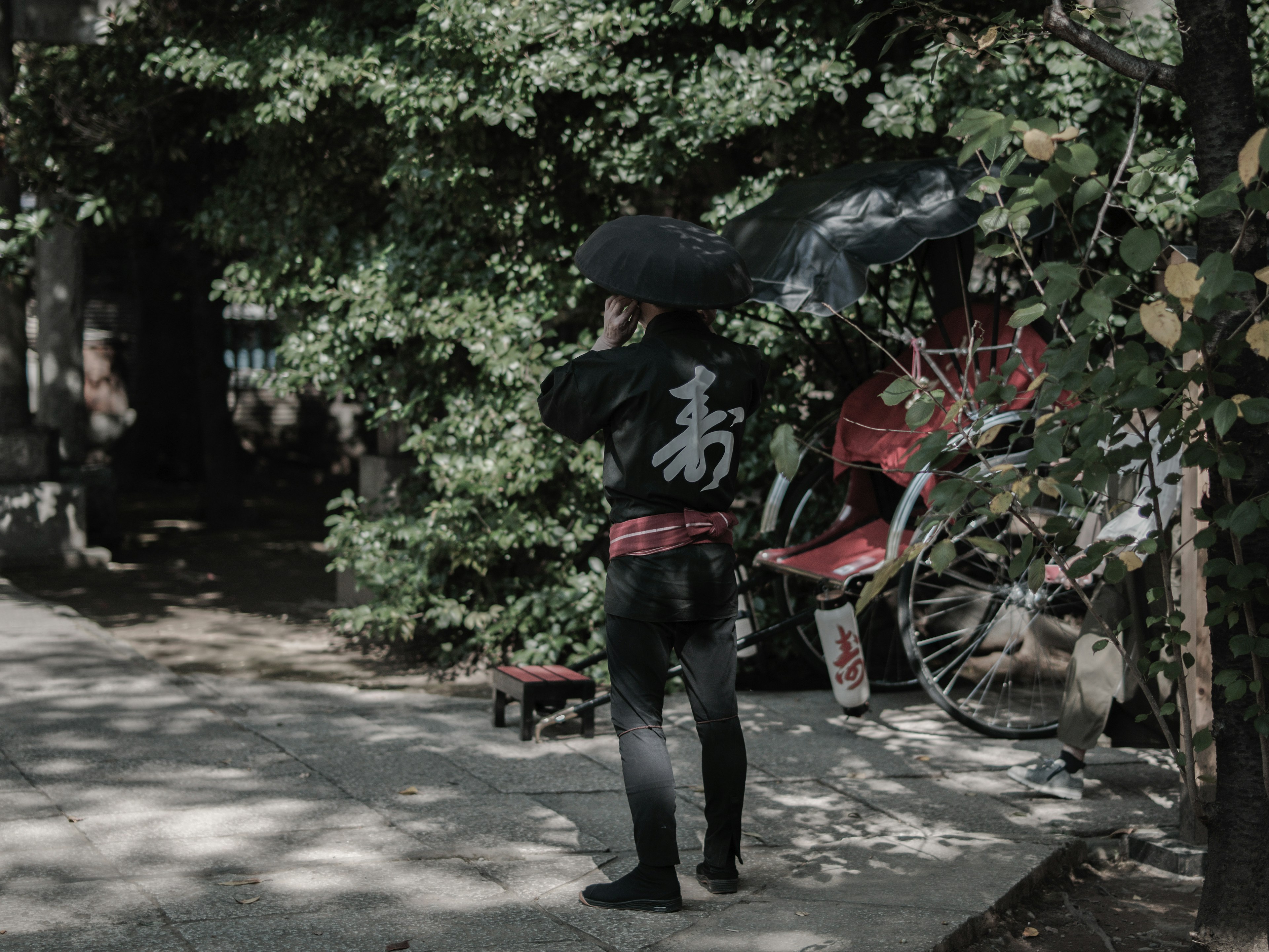 Persona con traje negro sosteniendo un paraguas con vegetación de fondo