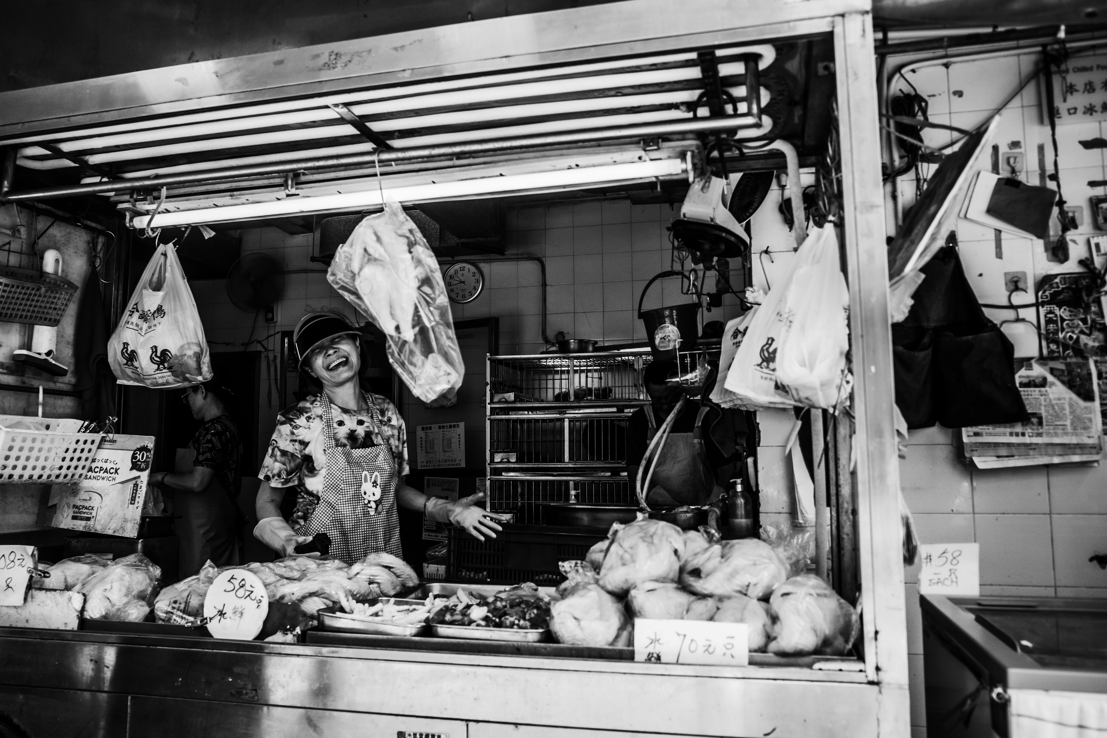 Photo en noir et blanc d'une boucherie avec le propriétaire souriant aux clients