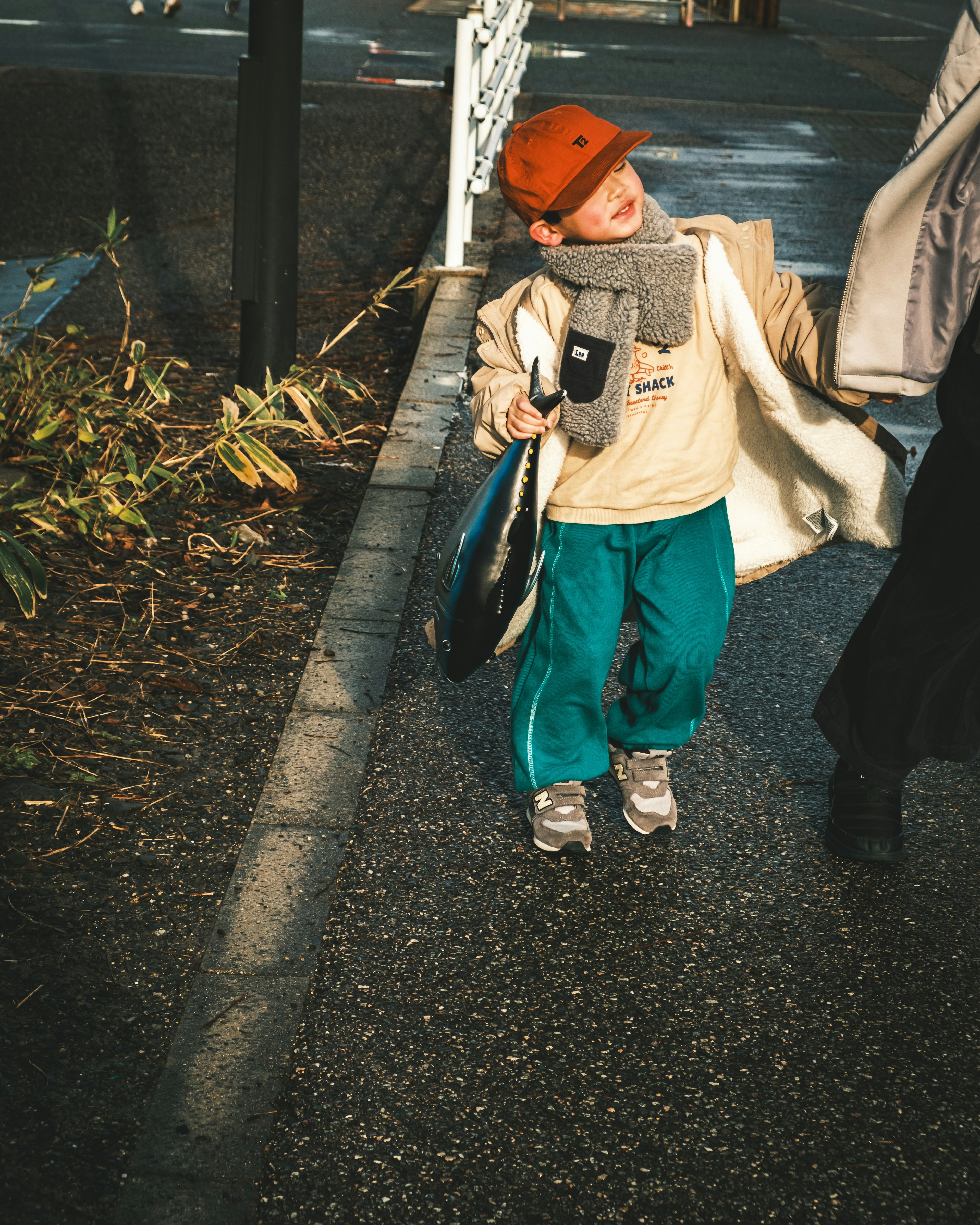 Bambino con un cappello rosso e una sciarpa che cammina su un marciapiede