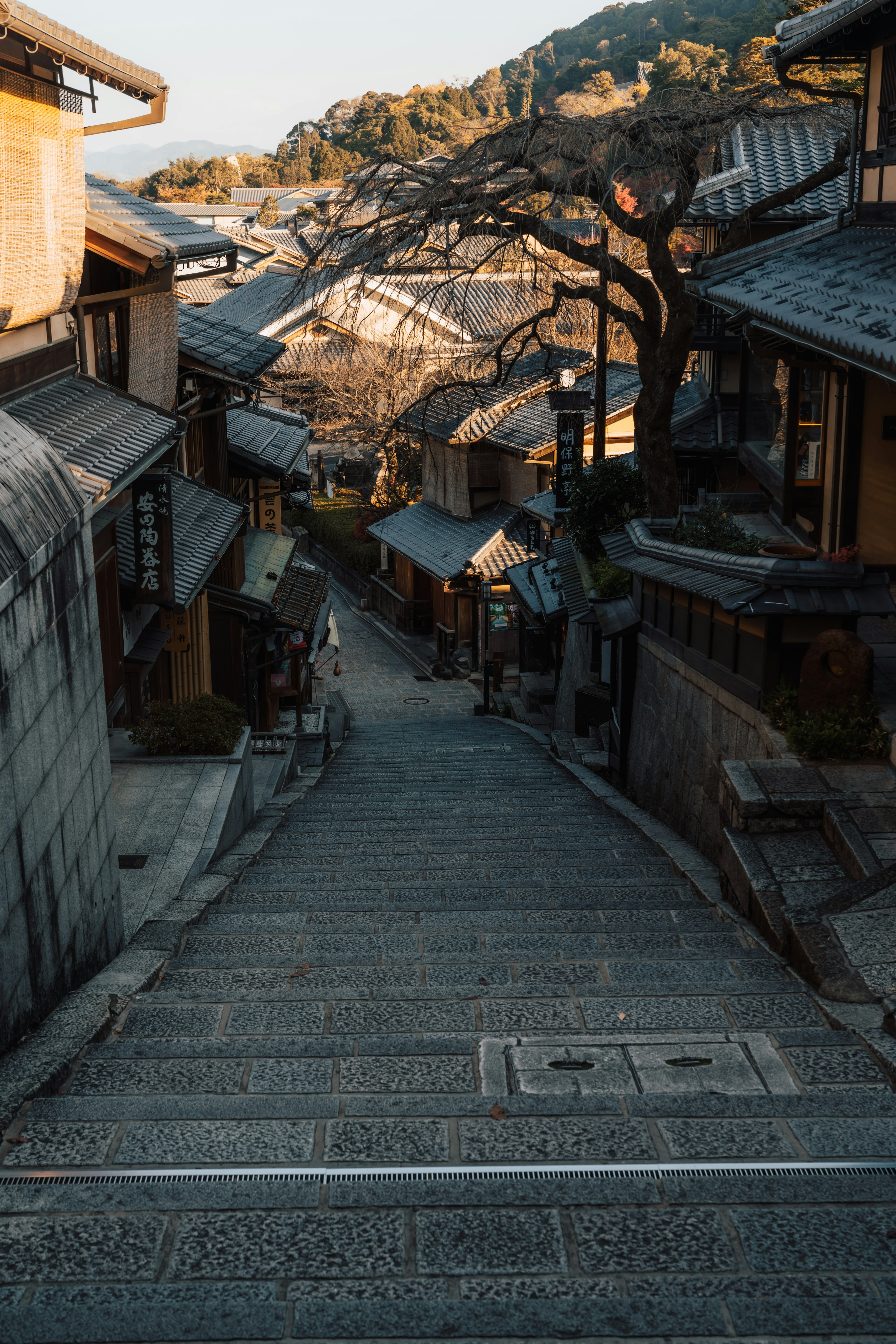 Jalan menanjak berbatu yang tenang dengan rumah tradisional Jepang di latar belakang