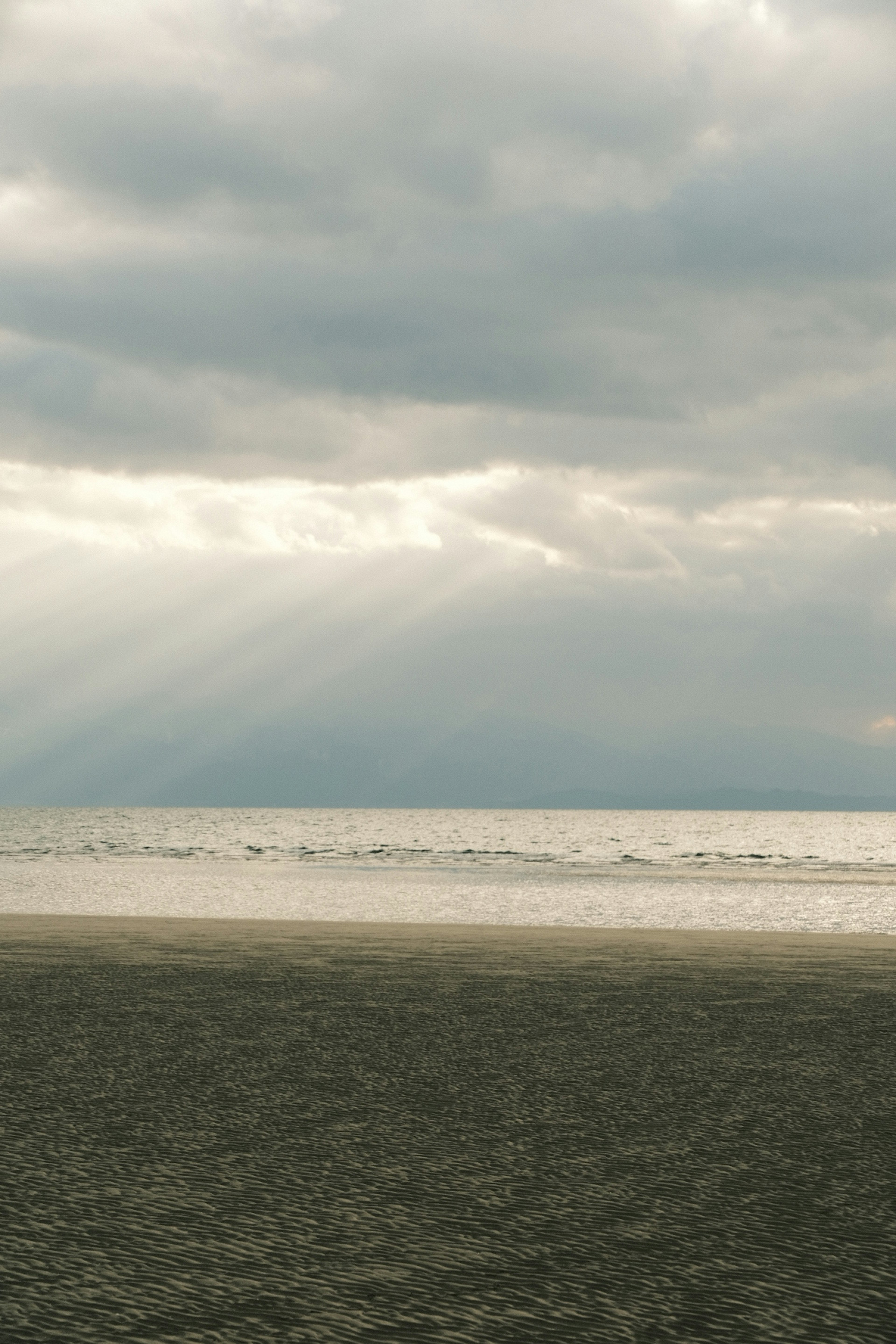 Paesaggio di spiaggia calma sotto le nuvole con raggi di sole