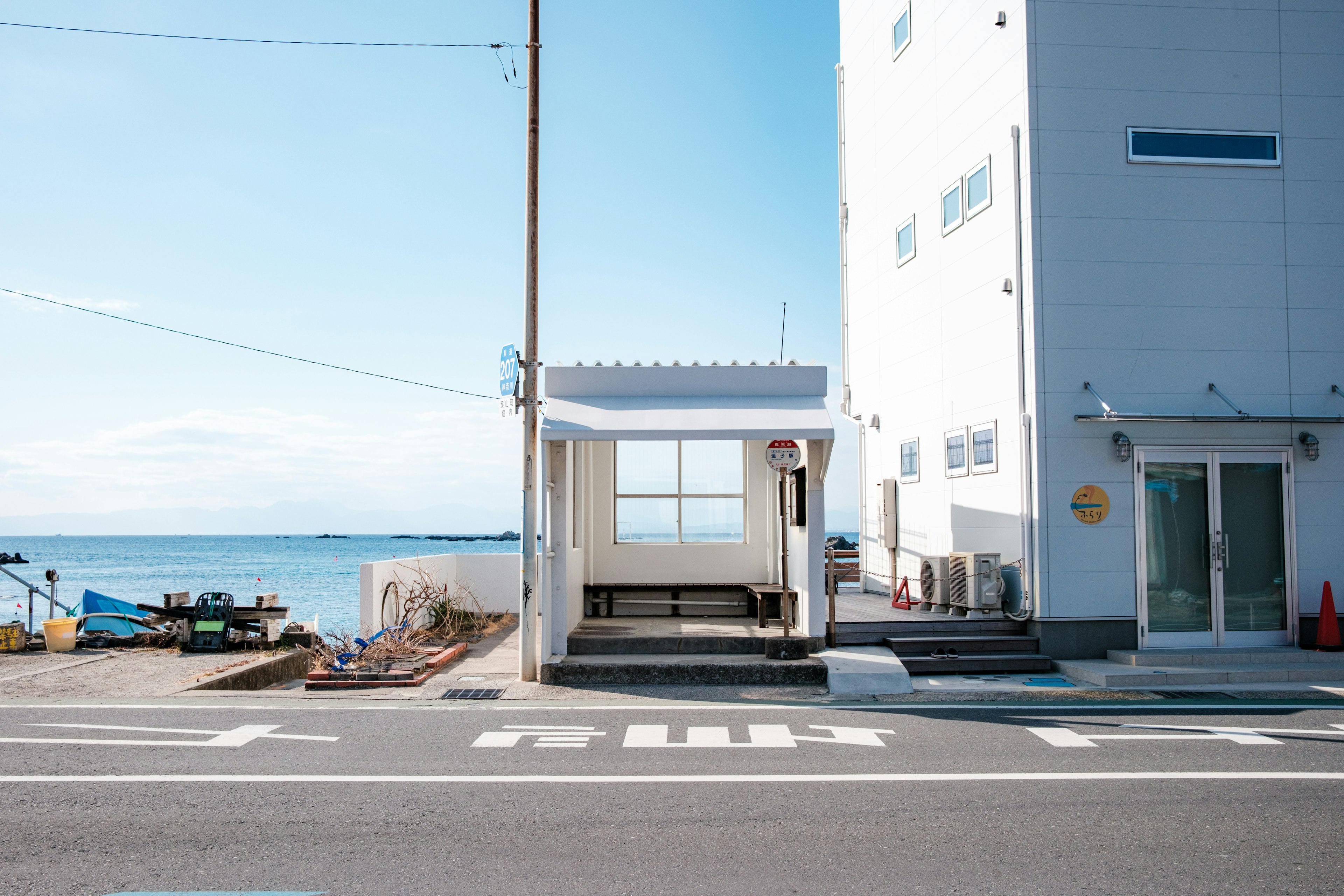 海の近くにある白い建物とベンチがある待合室