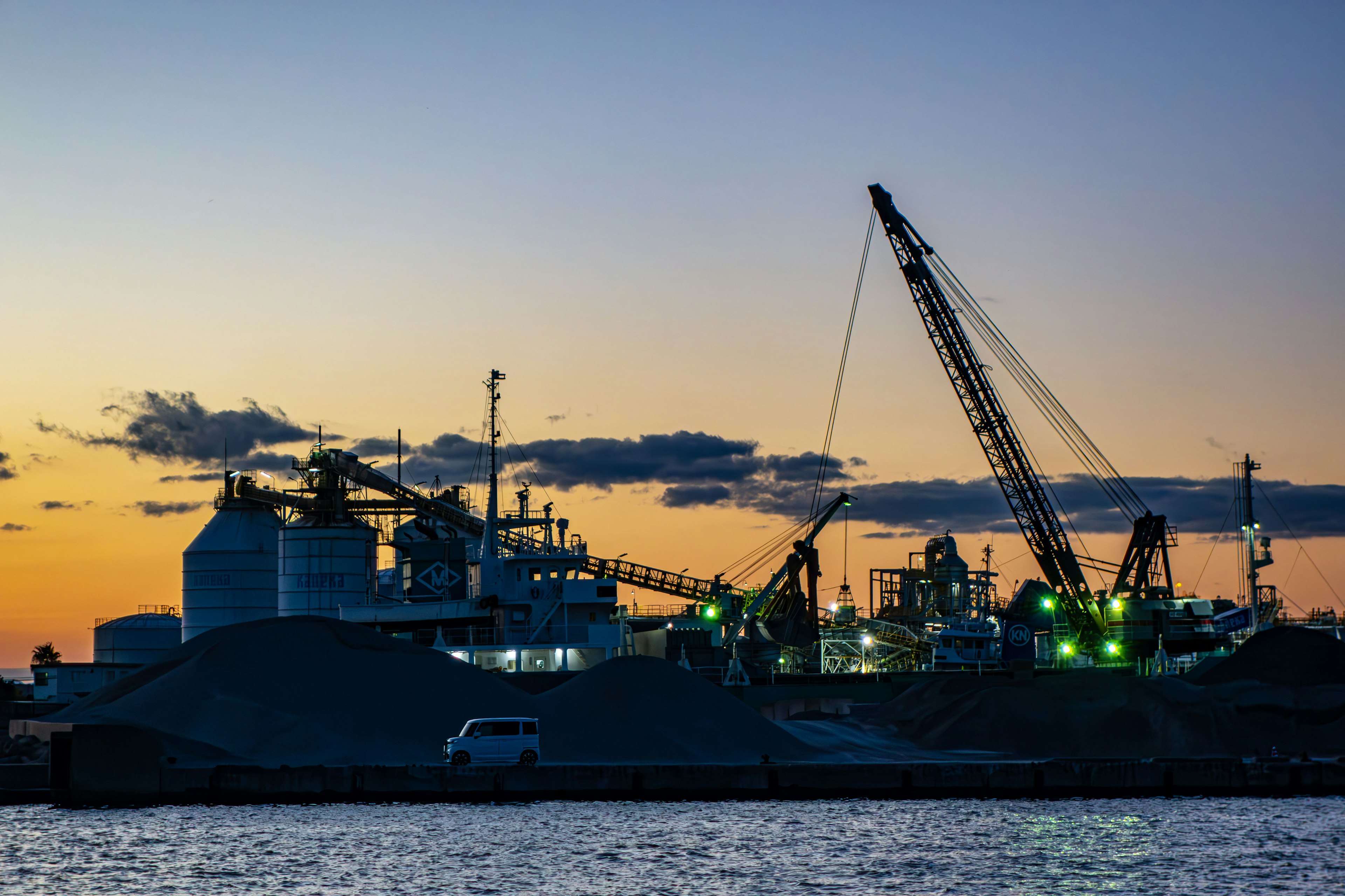 Industriehafen bei Sonnenuntergang mit Kränen und silhouettierten Gebäuden