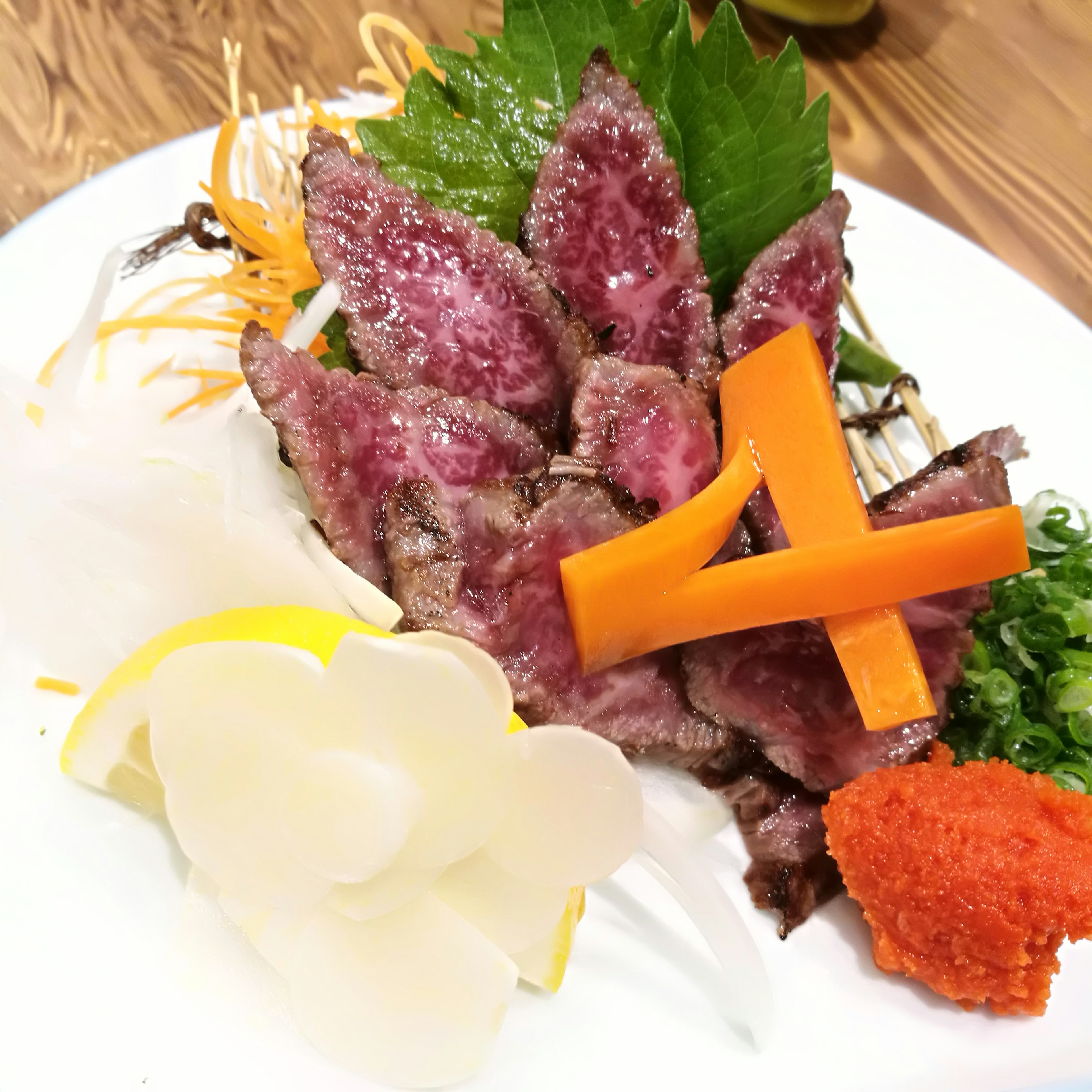 Colorful sashimi plate featuring thinly sliced meat and vegetables