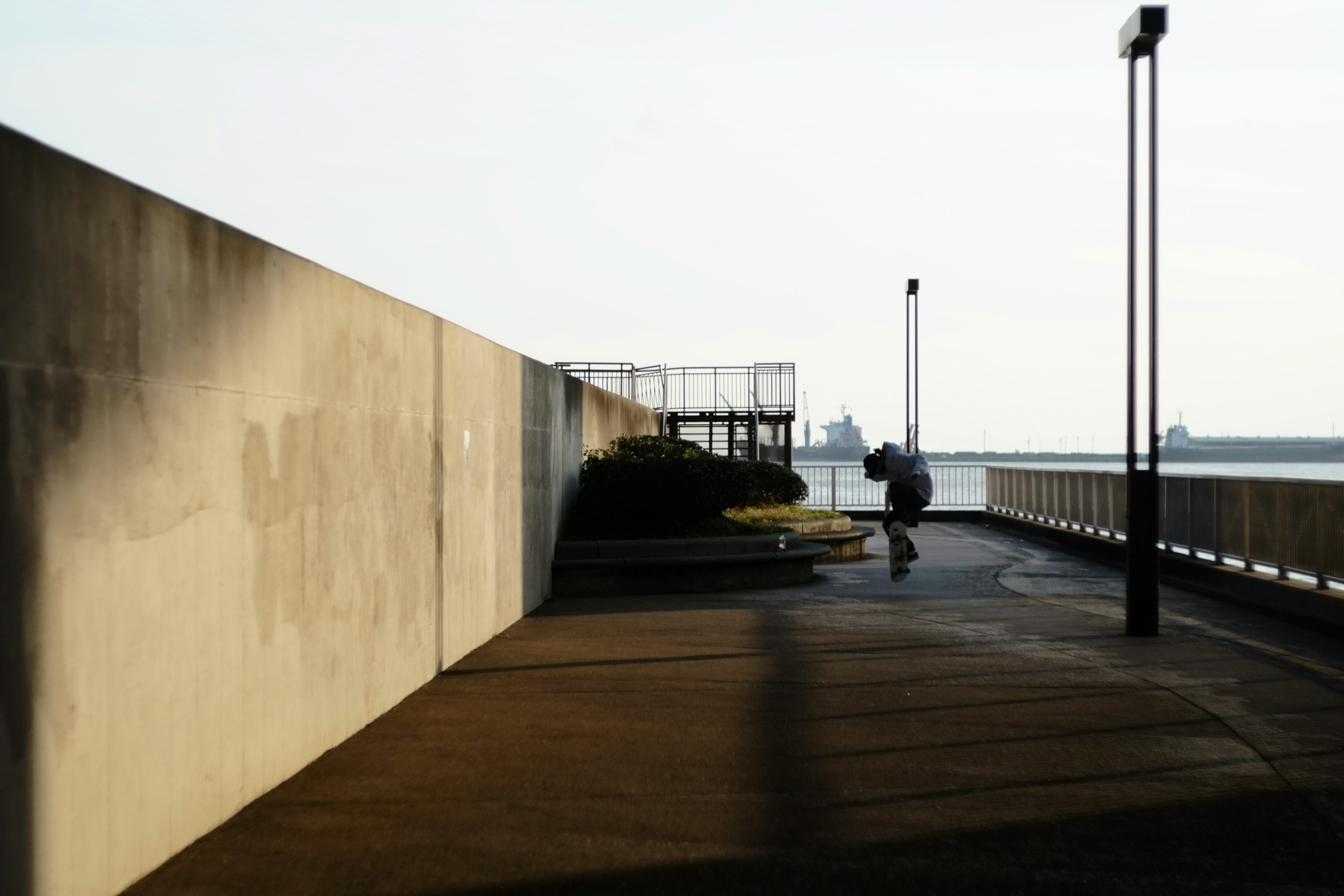 海の近くの歩道にいる人とコンクリートの壁の風景