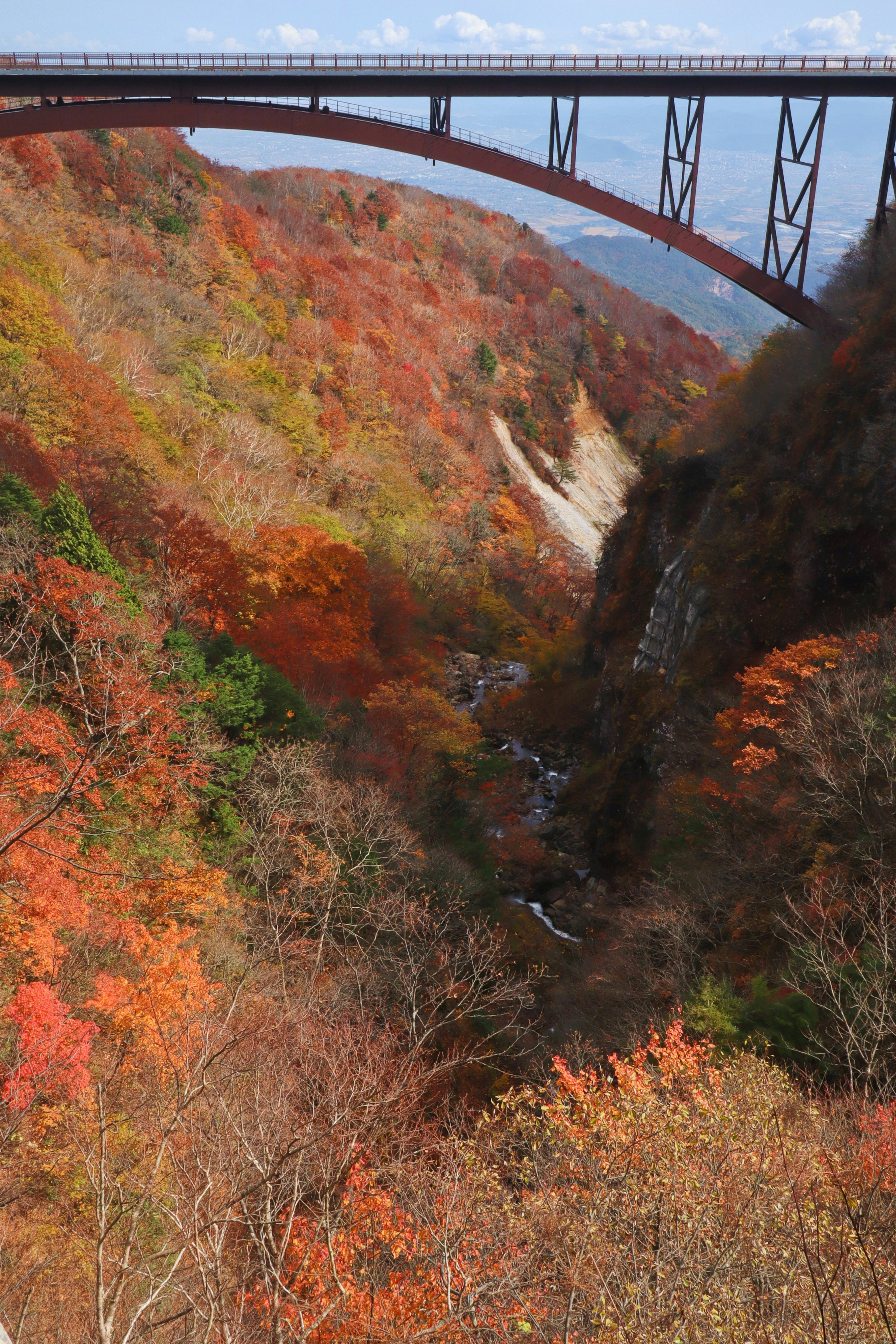 Scenic autumn valley with vibrant foliage and a red bridge