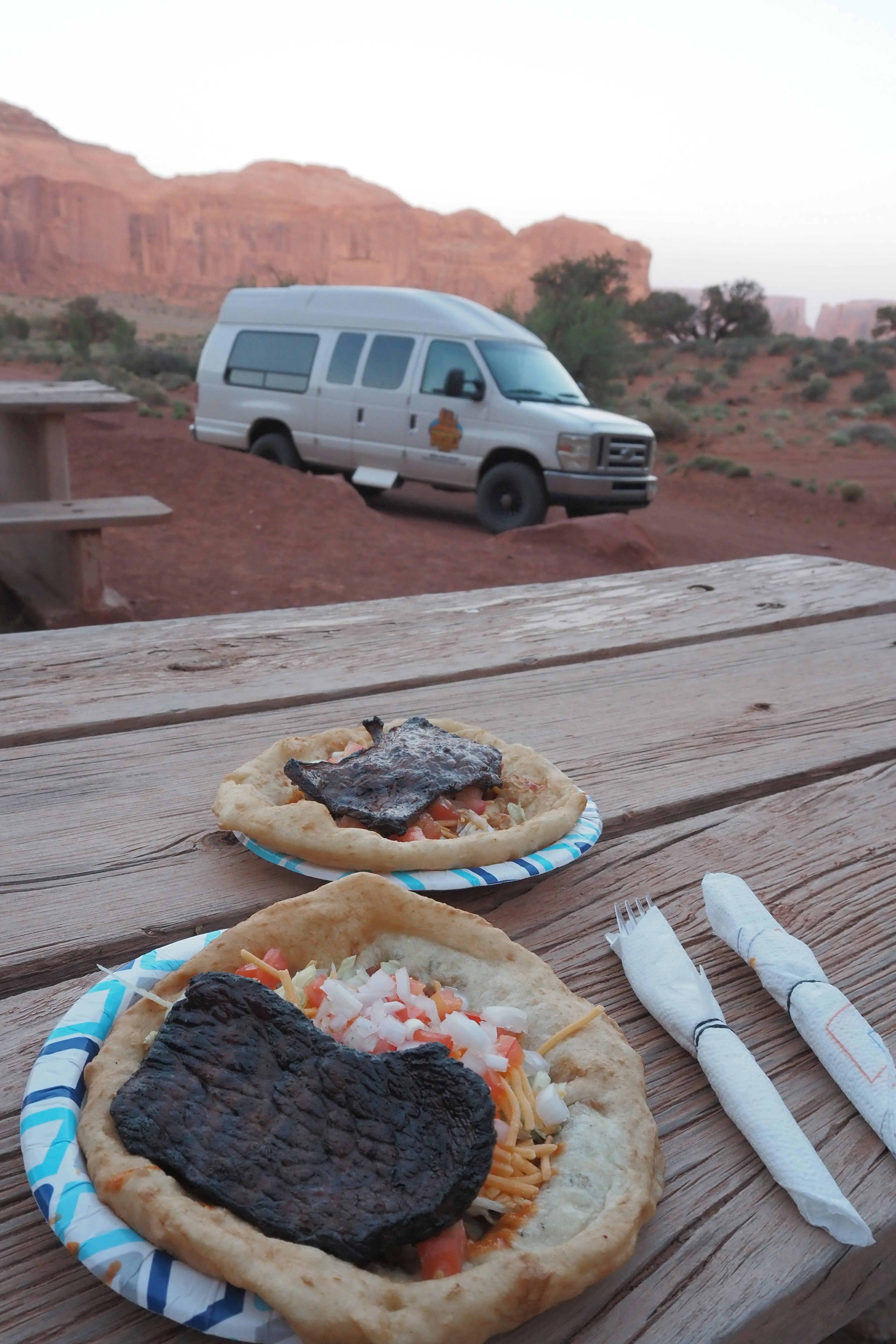 Abendessen mit Blick auf rote Felsformationen und einen Campingbus