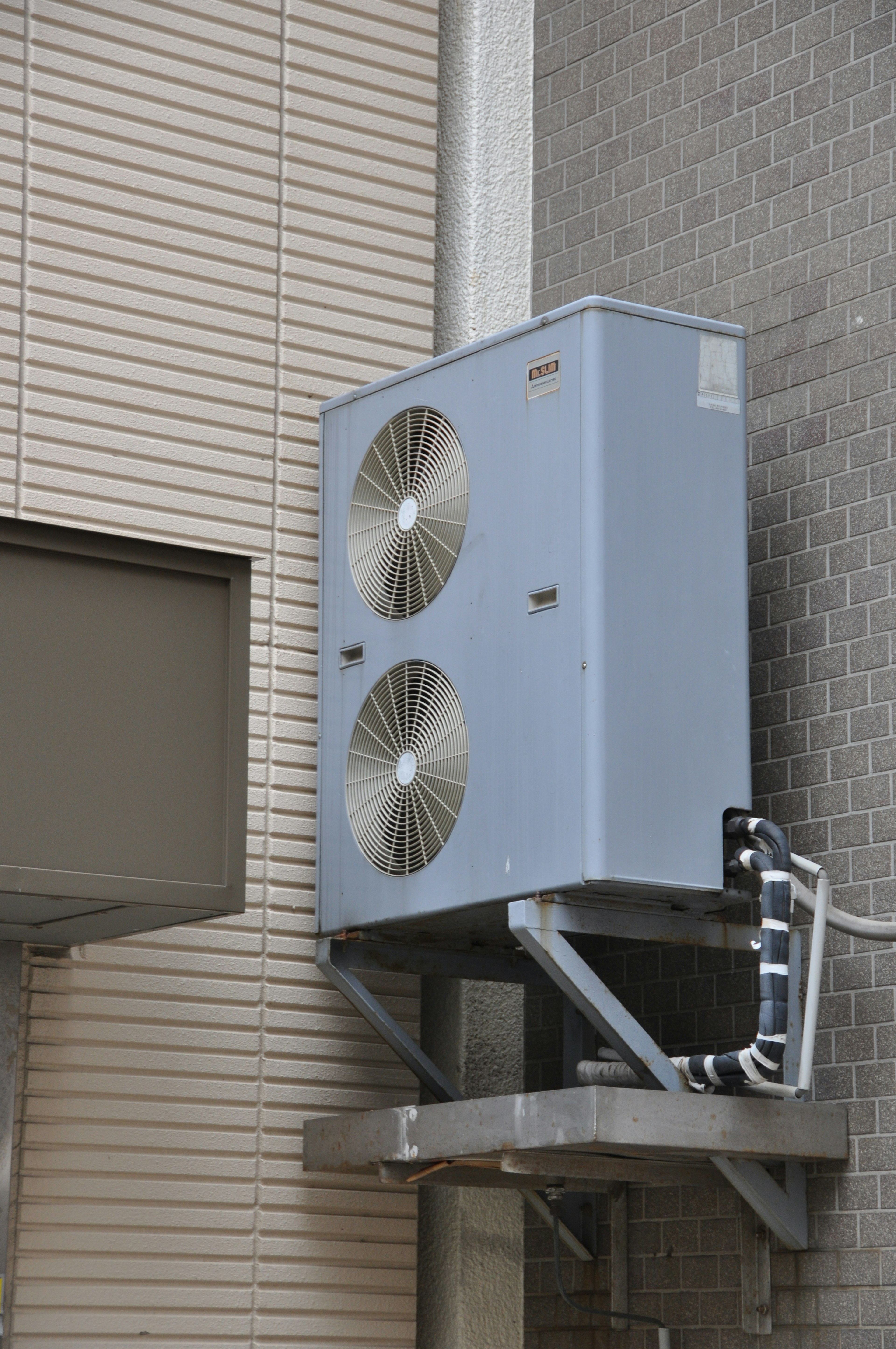 Outdoor air conditioning unit mounted on the wall featuring silver and gray design