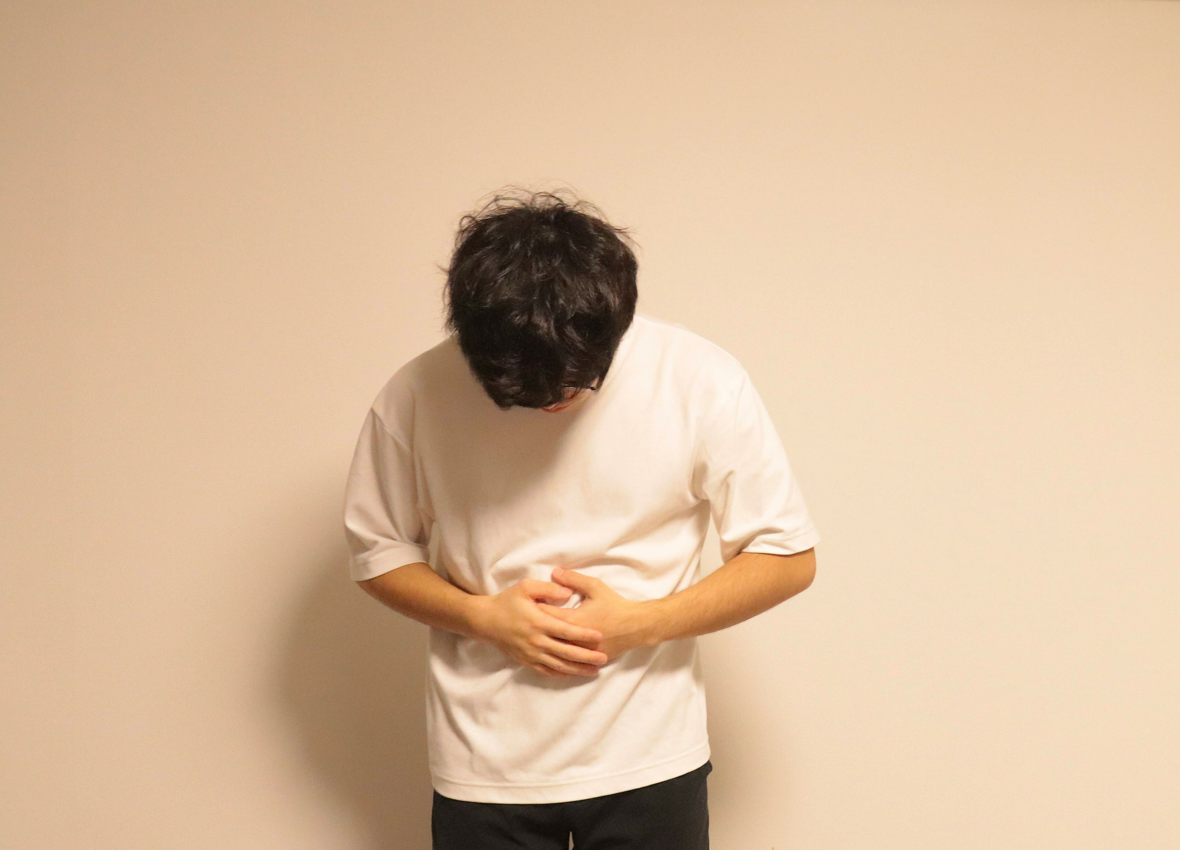 A man wearing a white t-shirt holding his stomach