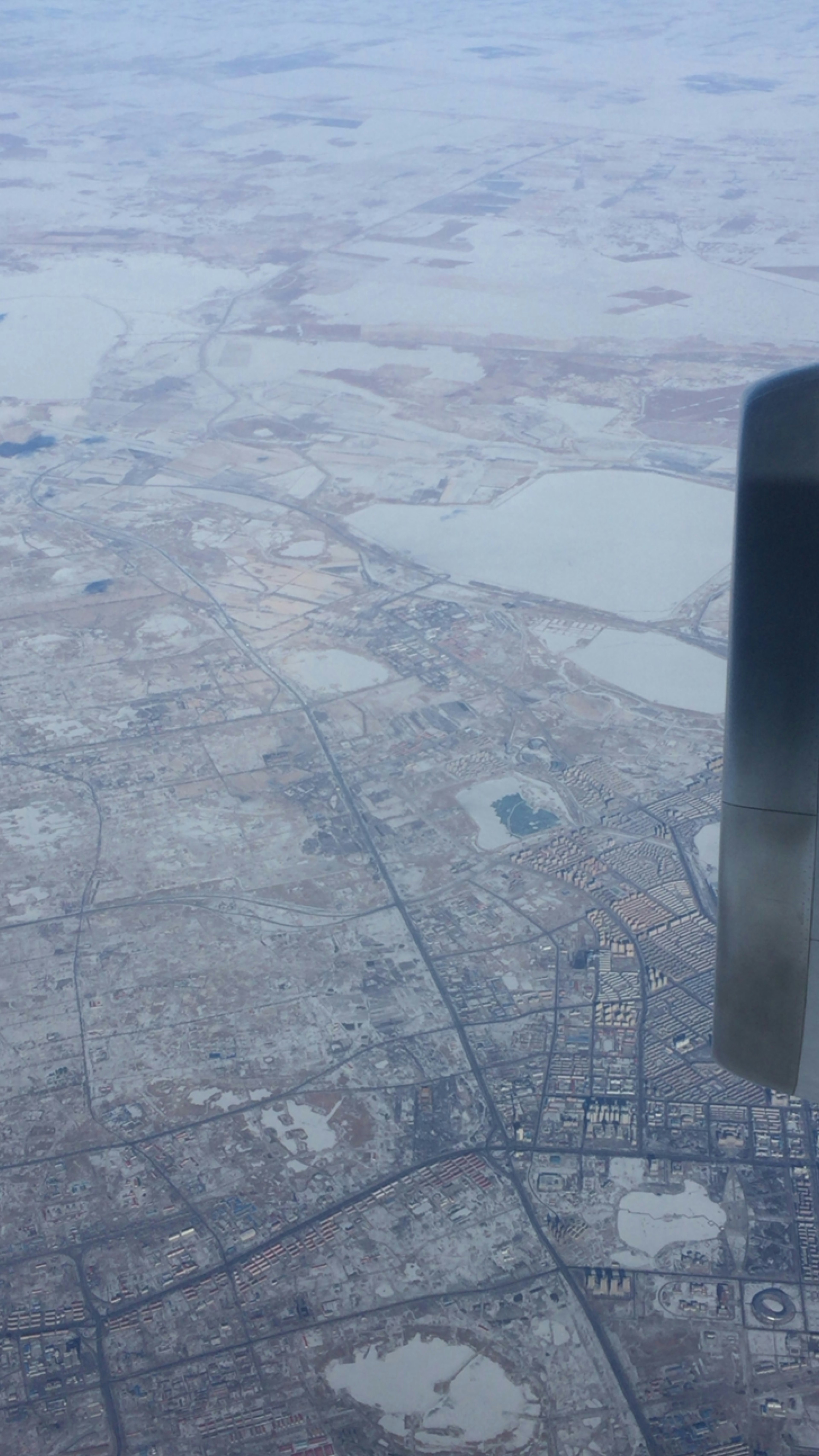 Vista aerea di una città coperta di neve con un'ala di aereo