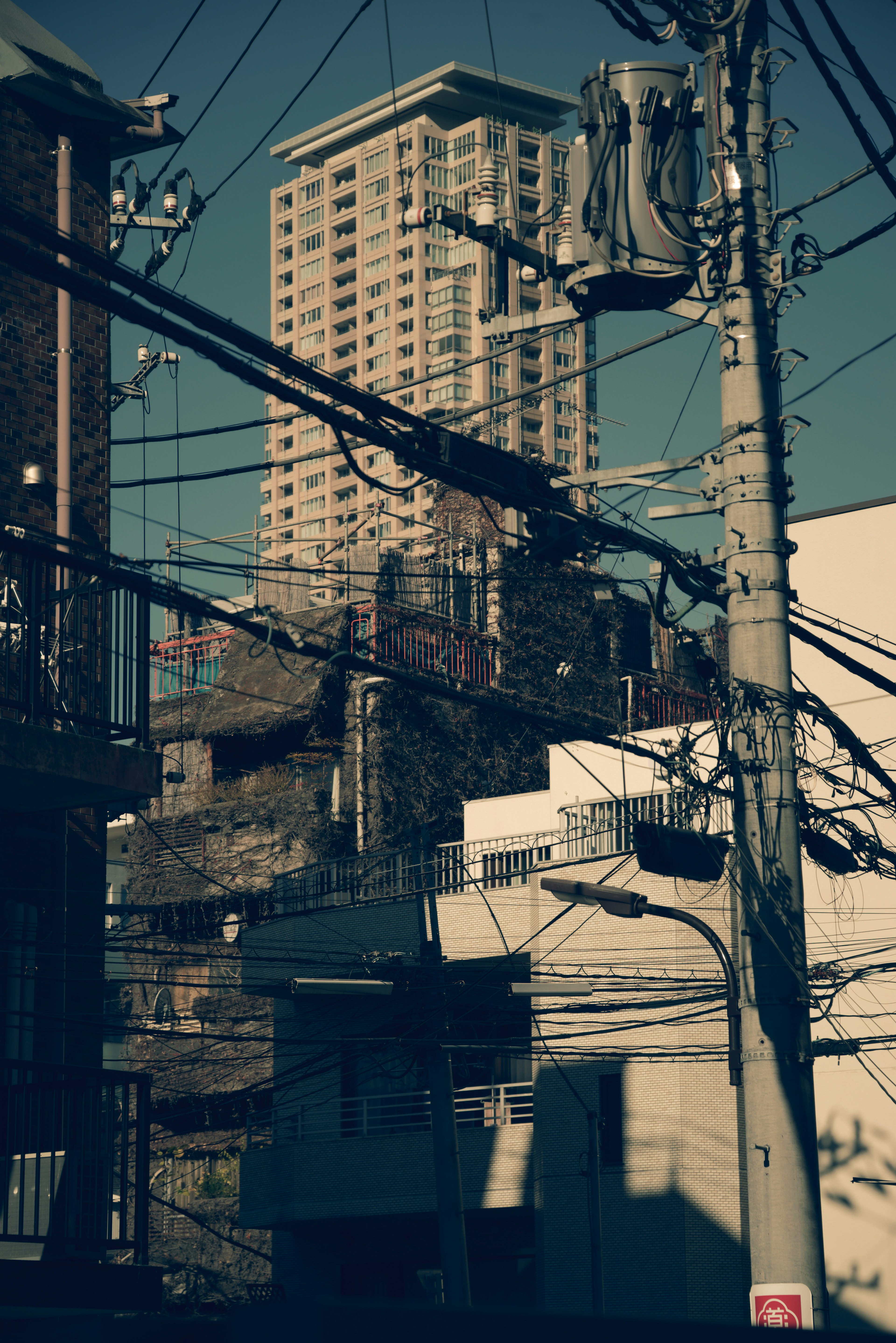 Escena urbana con edificio de gran altura y líneas eléctricas