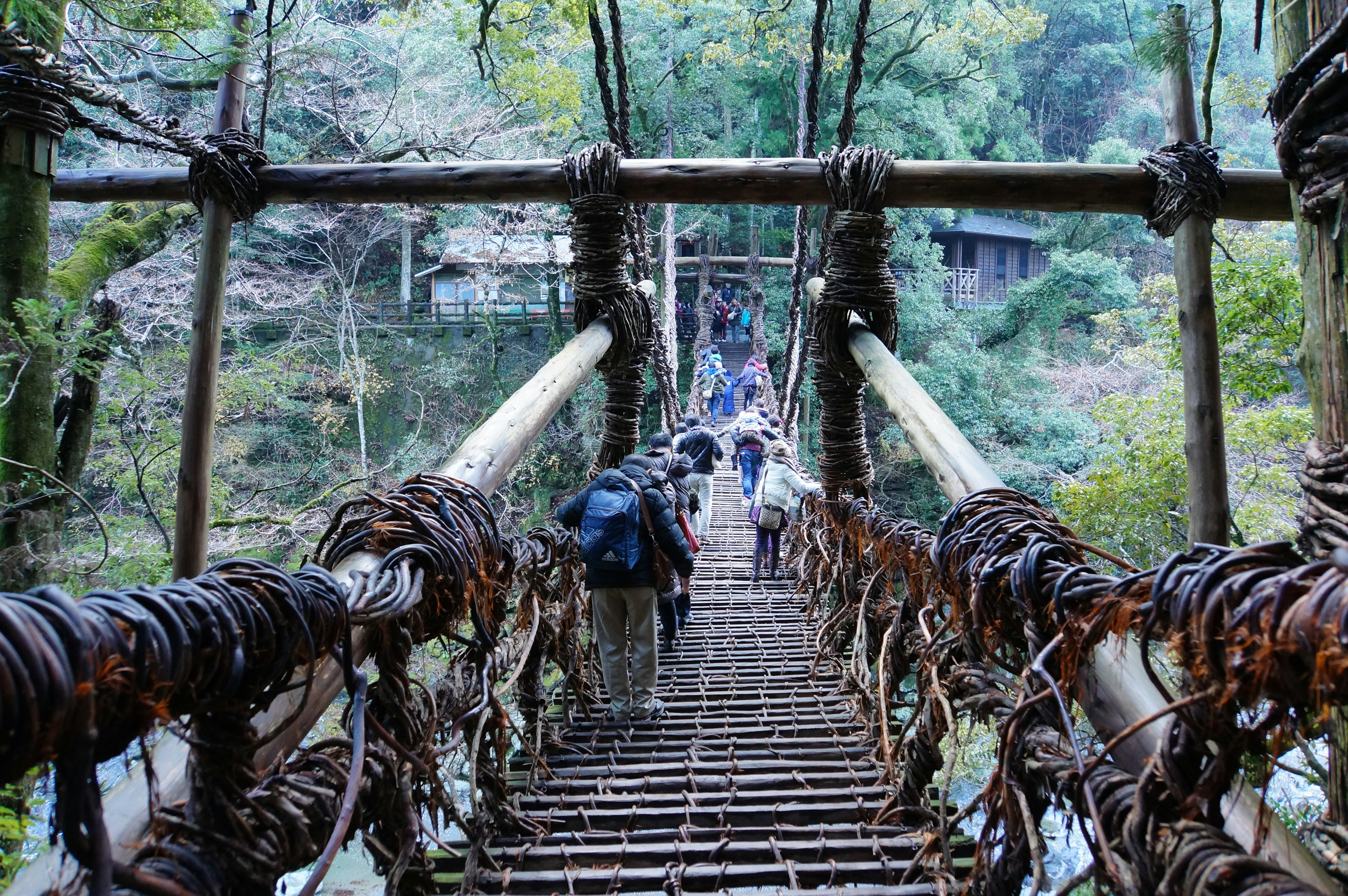 Personas cruzando un viejo puente colgante rodeado de naturaleza